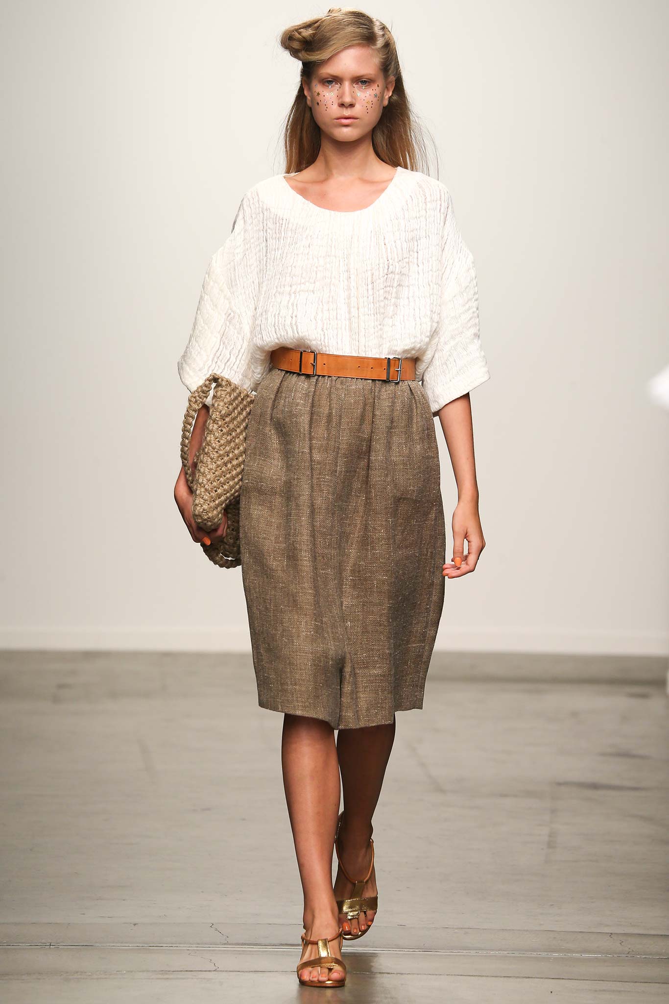 A relaxed white blouse paired with a pleated brown skirt, featuring a belted waist.