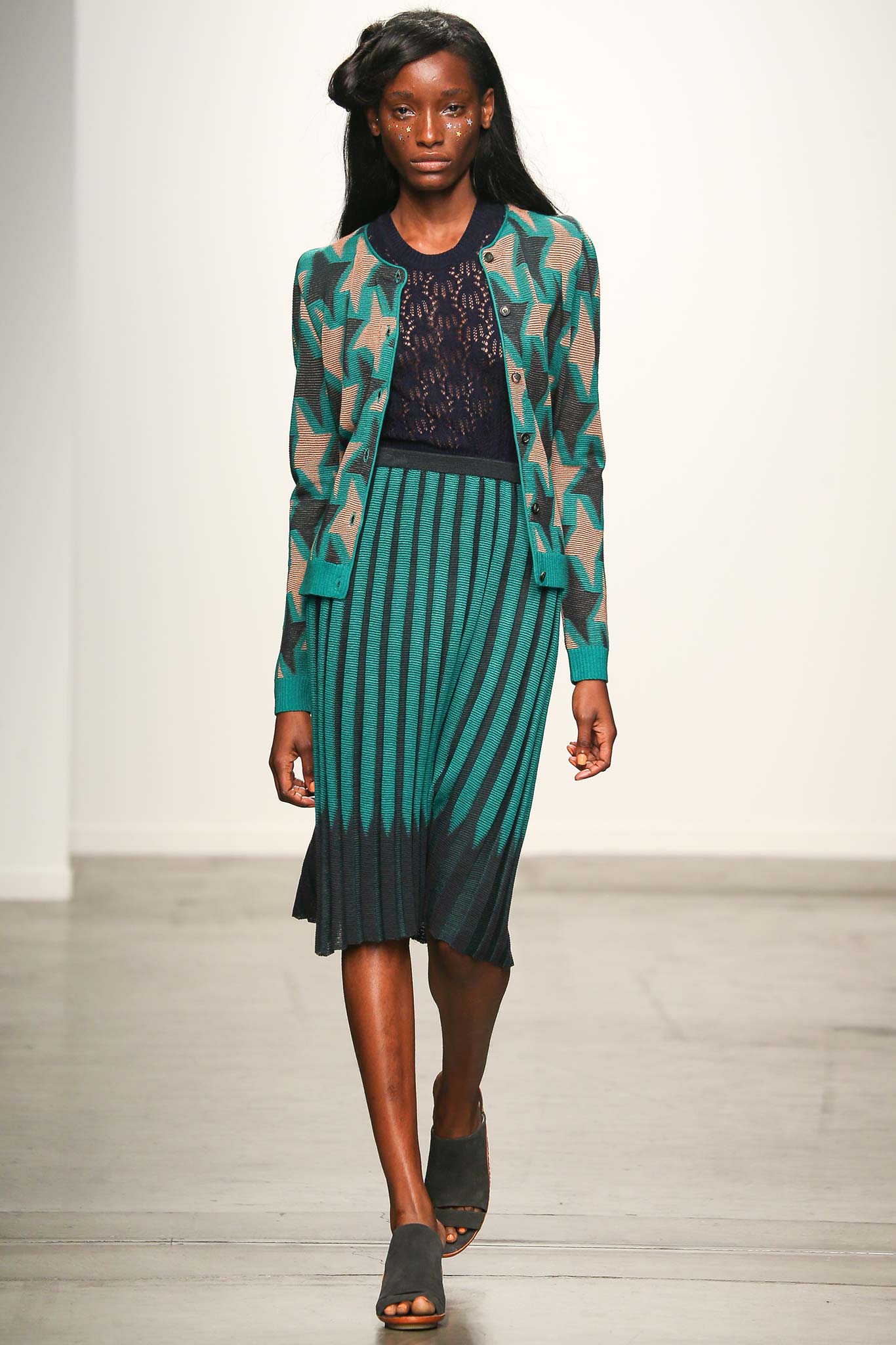 A fitted green and brown cardigan paired with a pleated navy skirt, perfect for a stylish look.