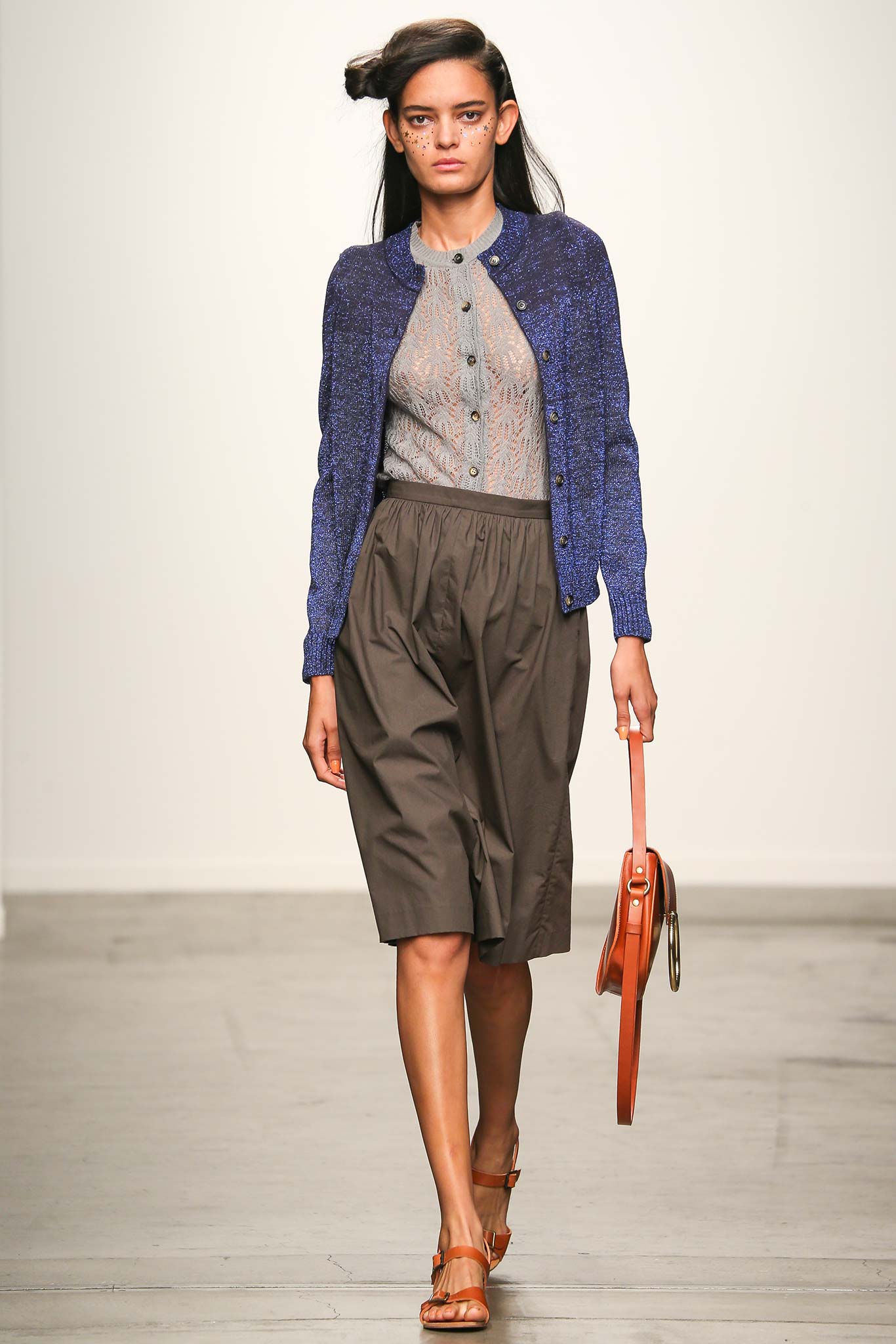 A relaxed gray cotton cardigan with a collared neckline paired with a pleated skirt.