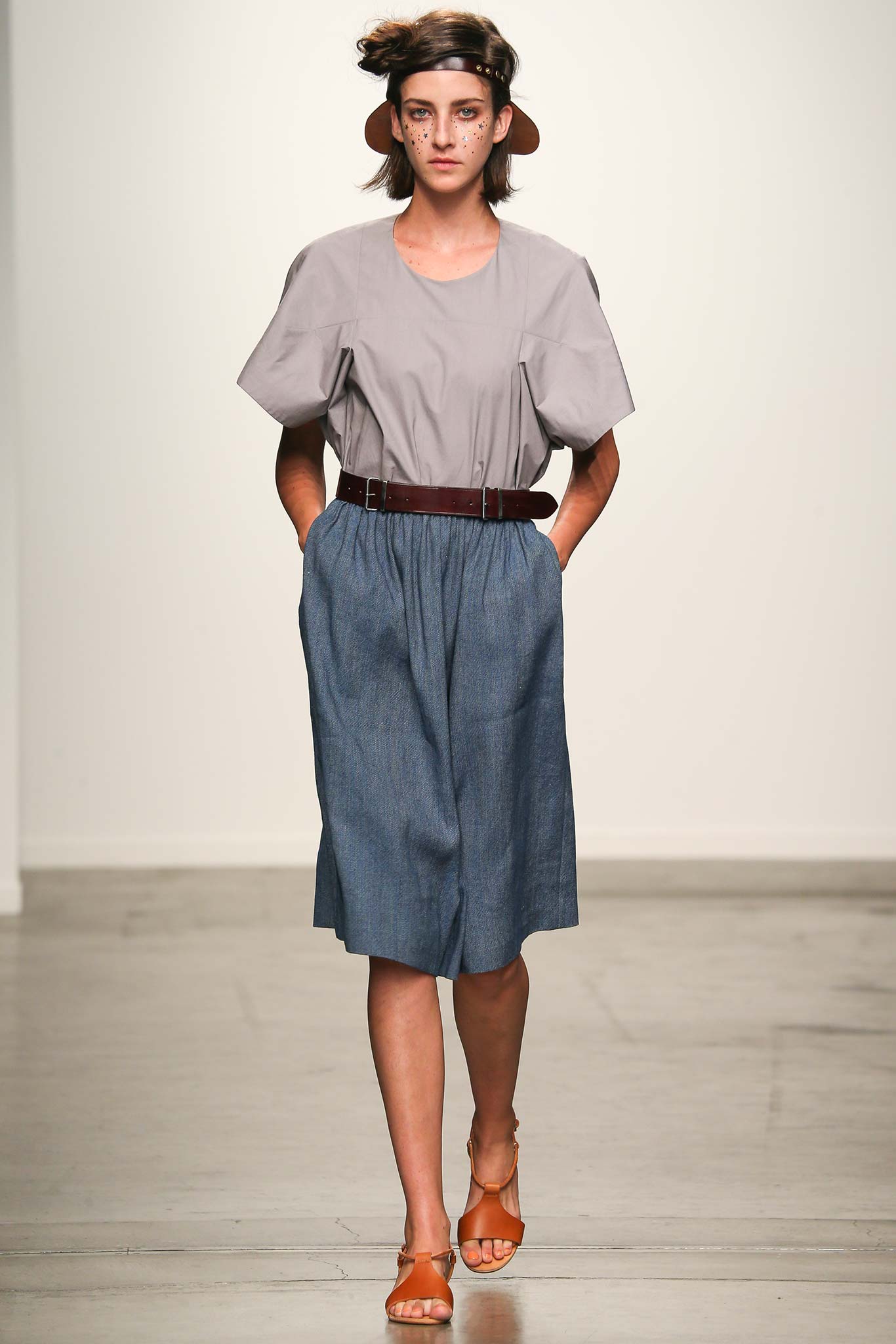 A relaxed gray cotton top with short sleeves paired with a pleated blue denim skirt, belted at the waist.