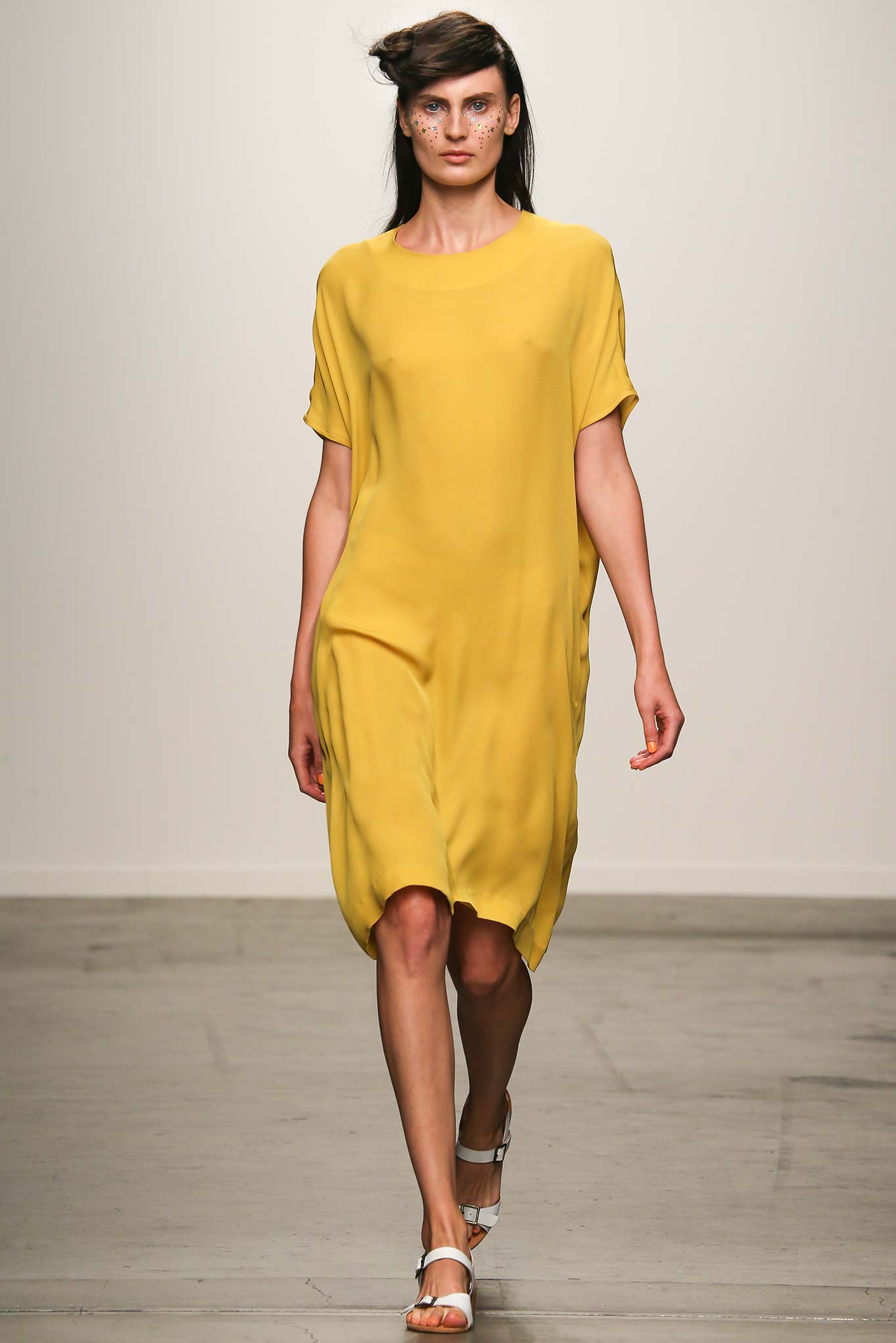 A relaxed yellow silk dress with short sleeves and an asymmetric hemline.
