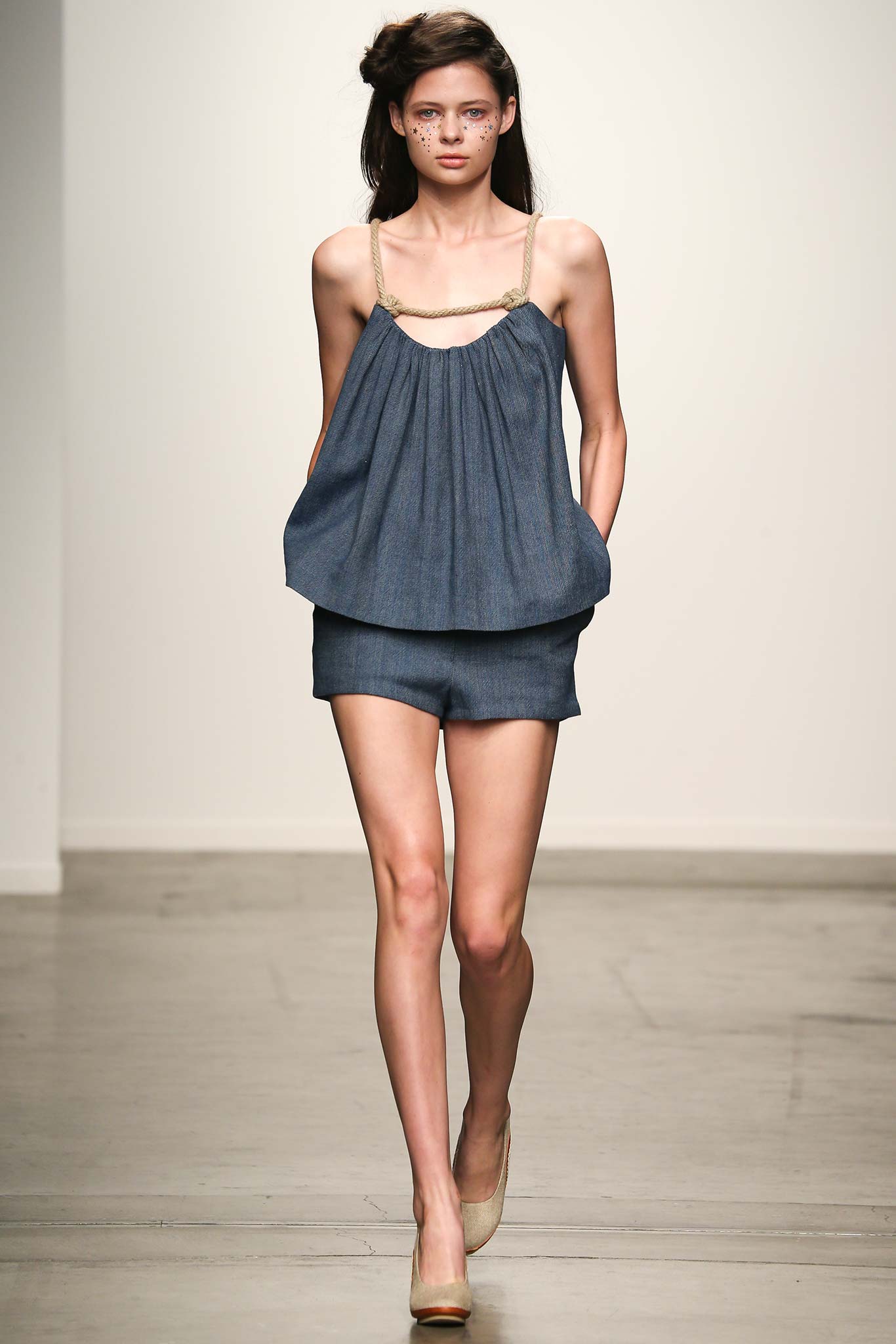 A relaxed blue denim sleeveless top paired with matching shorts featuring pleated details.