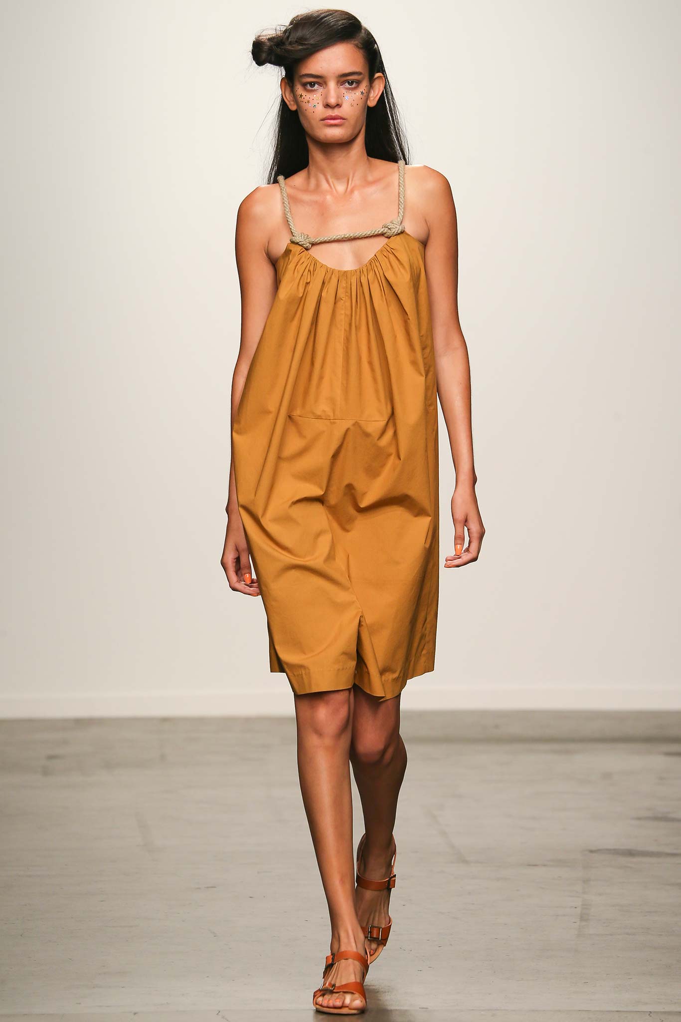 A relaxed brown cotton sleeveless dress with a V-neckline and tiered design.