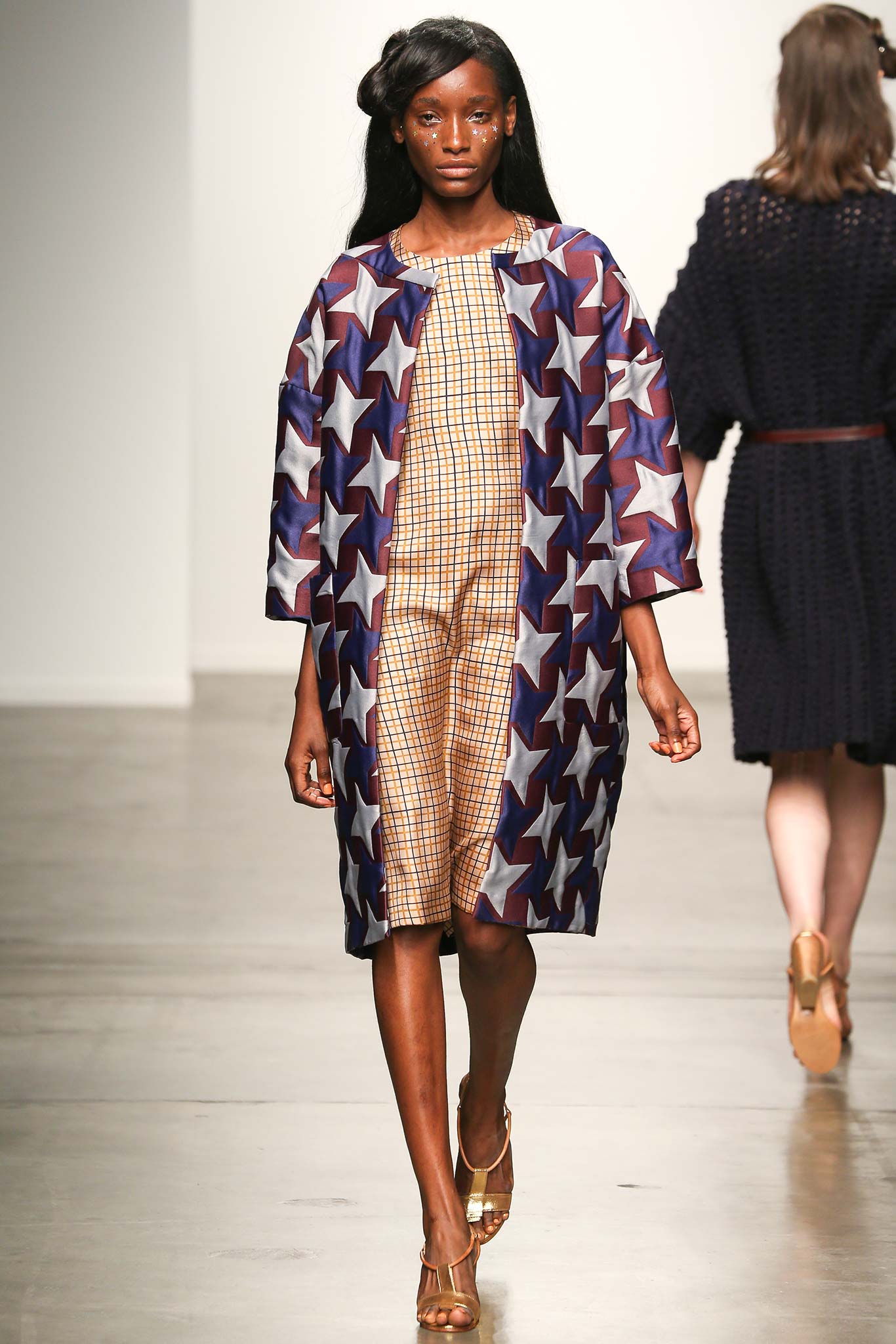 A fitted blue printed sleeveless dress with a collared coat overlay.