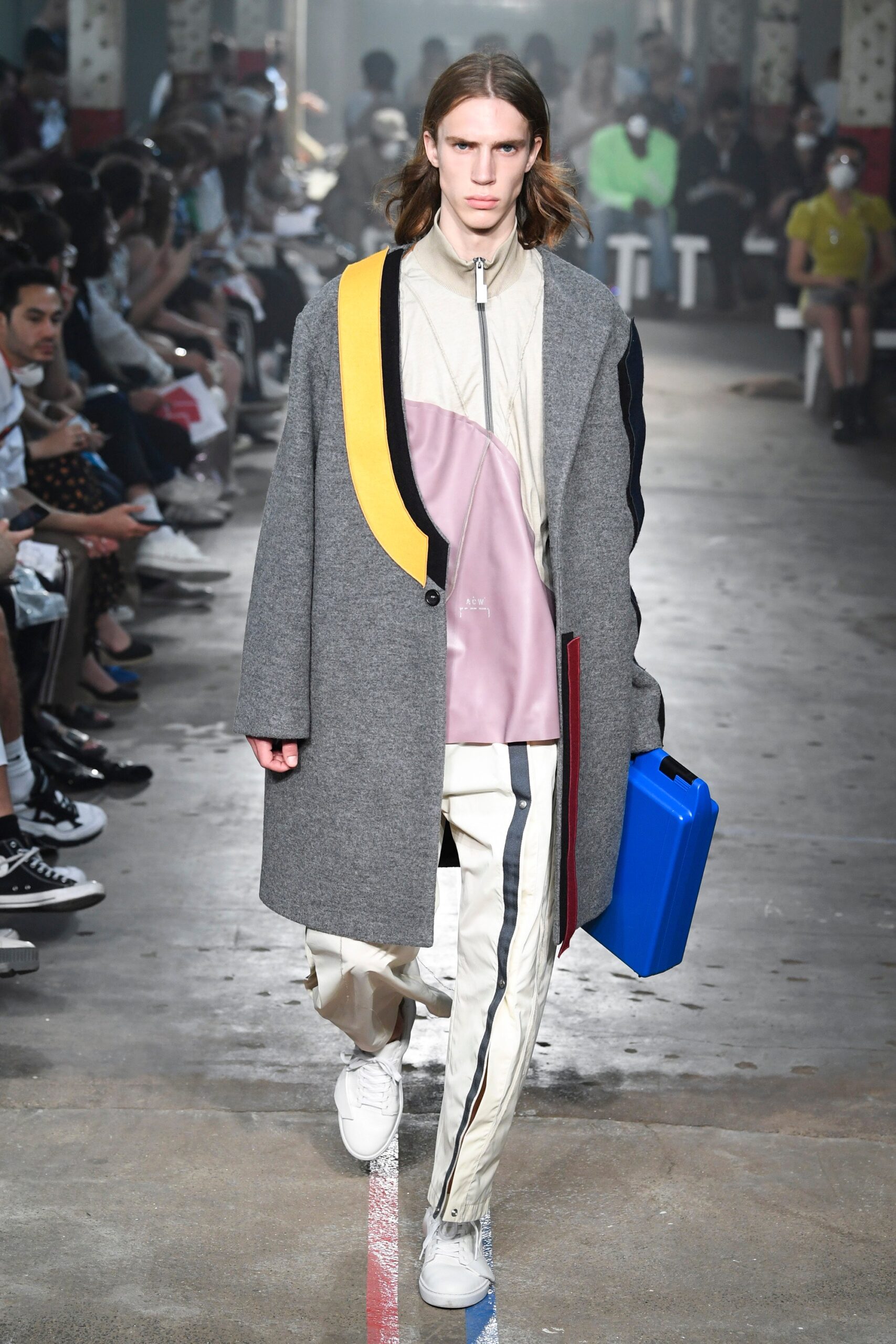 This coat features a relaxed silhouette, enhanced by a striking color-blocked design that incorporates shades of gray, pink, and blue. The long sleeves and collared neckline add a structured element, while the zippered details contribute to its contemporary aesthetic.