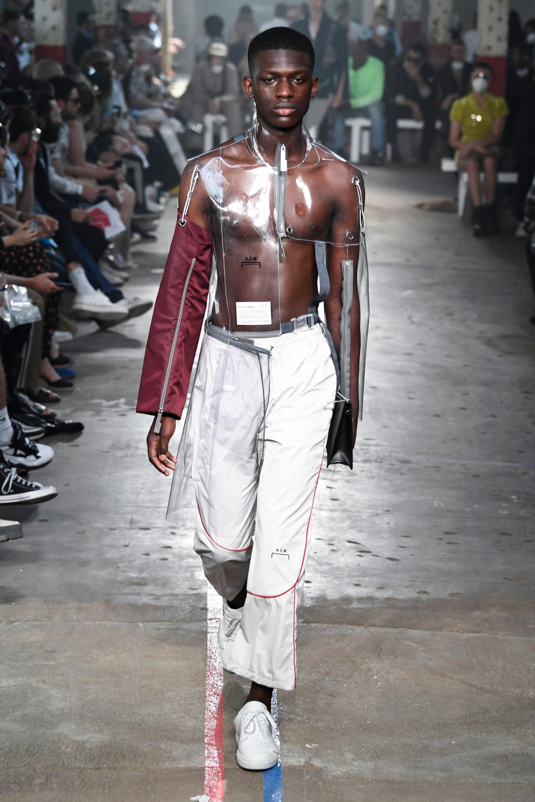 This striking jacket features a unique asymmetric design, crafted from transparent plastic that plays with light and movement. Paired with relaxed-fit pants, the ensemble creates a modern silhouette that challenges traditional fashion norms.