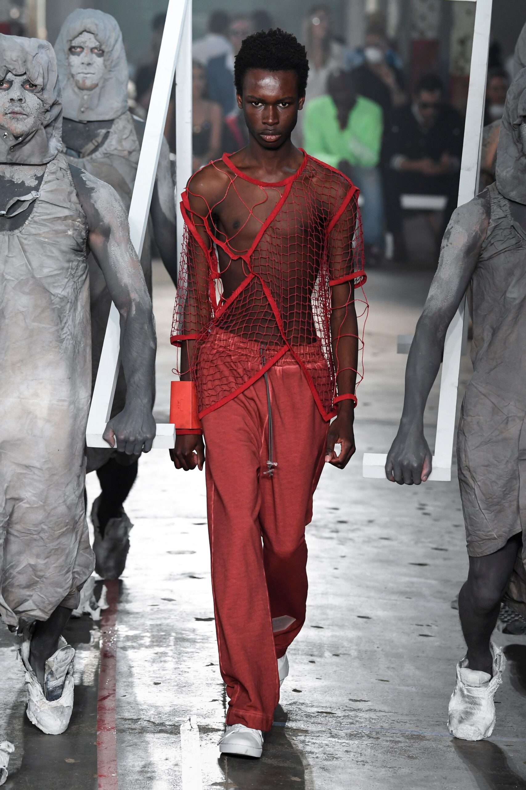 This ensemble features a relaxed top in a vibrant red, characterized by its asymmetric design and layered texture. Paired with matching pants, the look embodies a contemporary streetwear aesthetic, merging bold color with innovative construction.