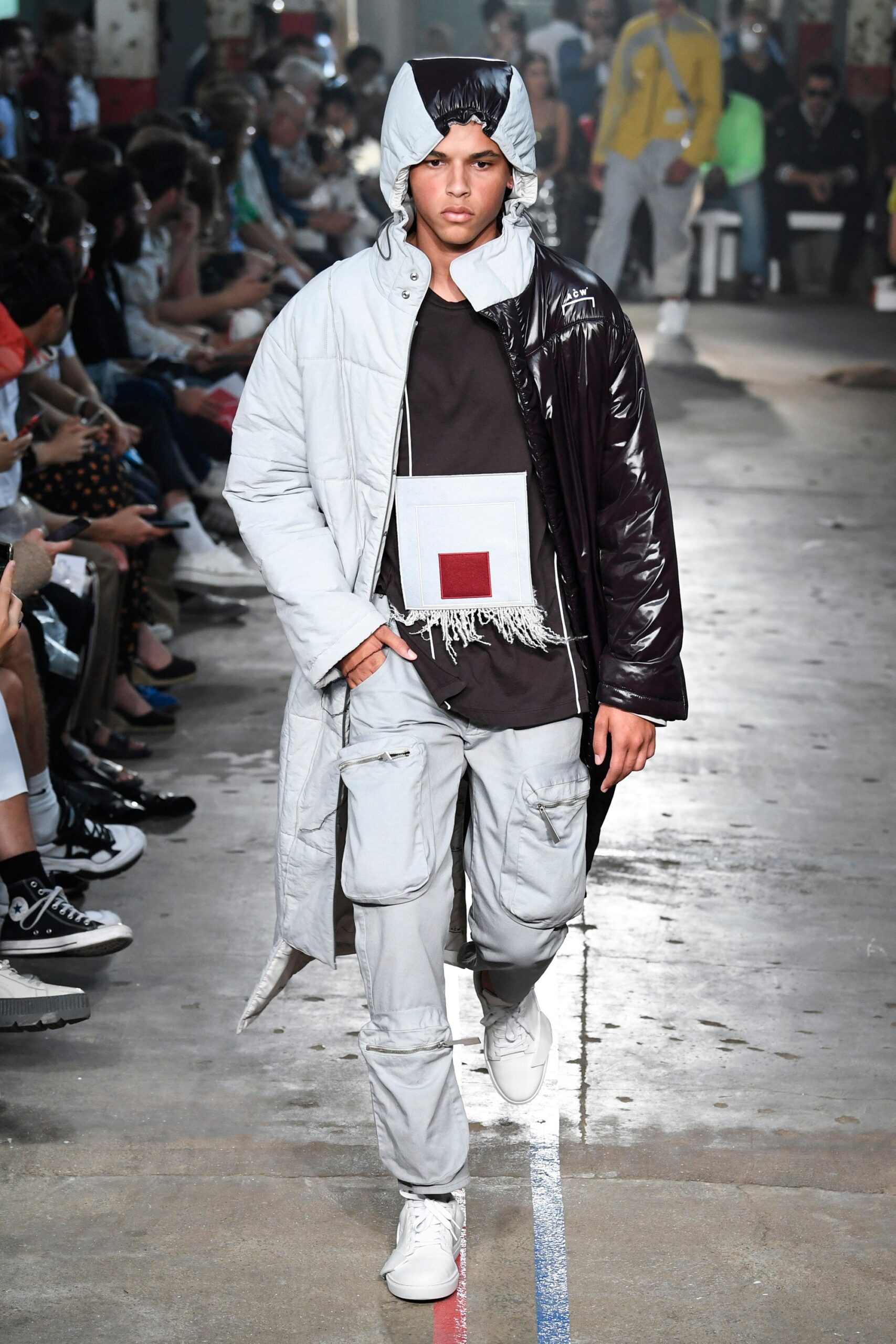 This relaxed coat features a striking combination of black and gray, showcasing a unique layered design that plays with proportions. The hood adds an element of functionality, while the zippered details enhance its contemporary aesthetic.