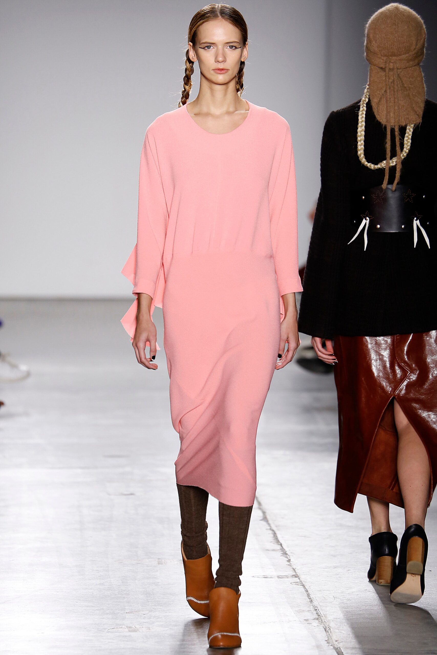 A fitted pink knit dress with a V-neckline and asymmetric design detail.