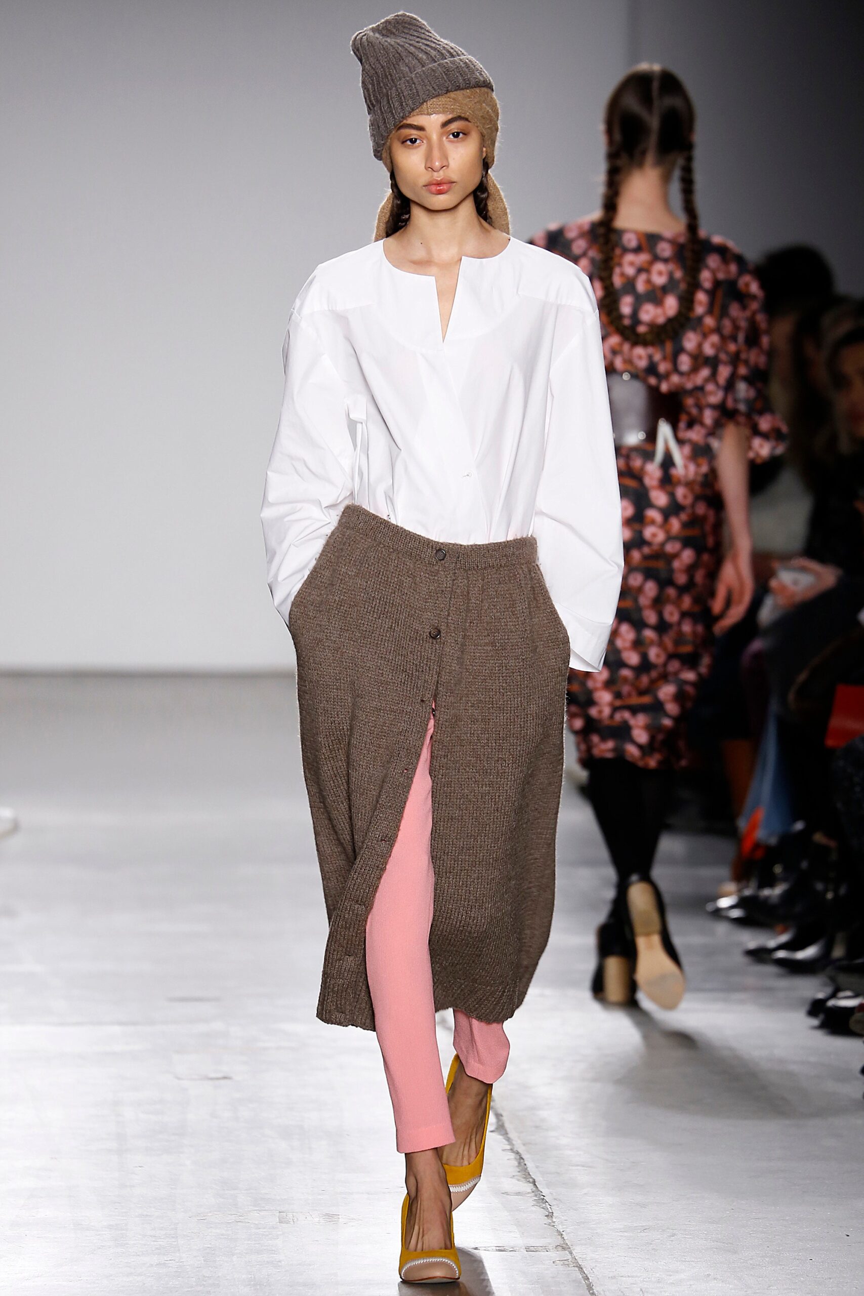 A relaxed white long-sleeve collared shirt paired with a buttoned brown knit skirt and pink pants.
