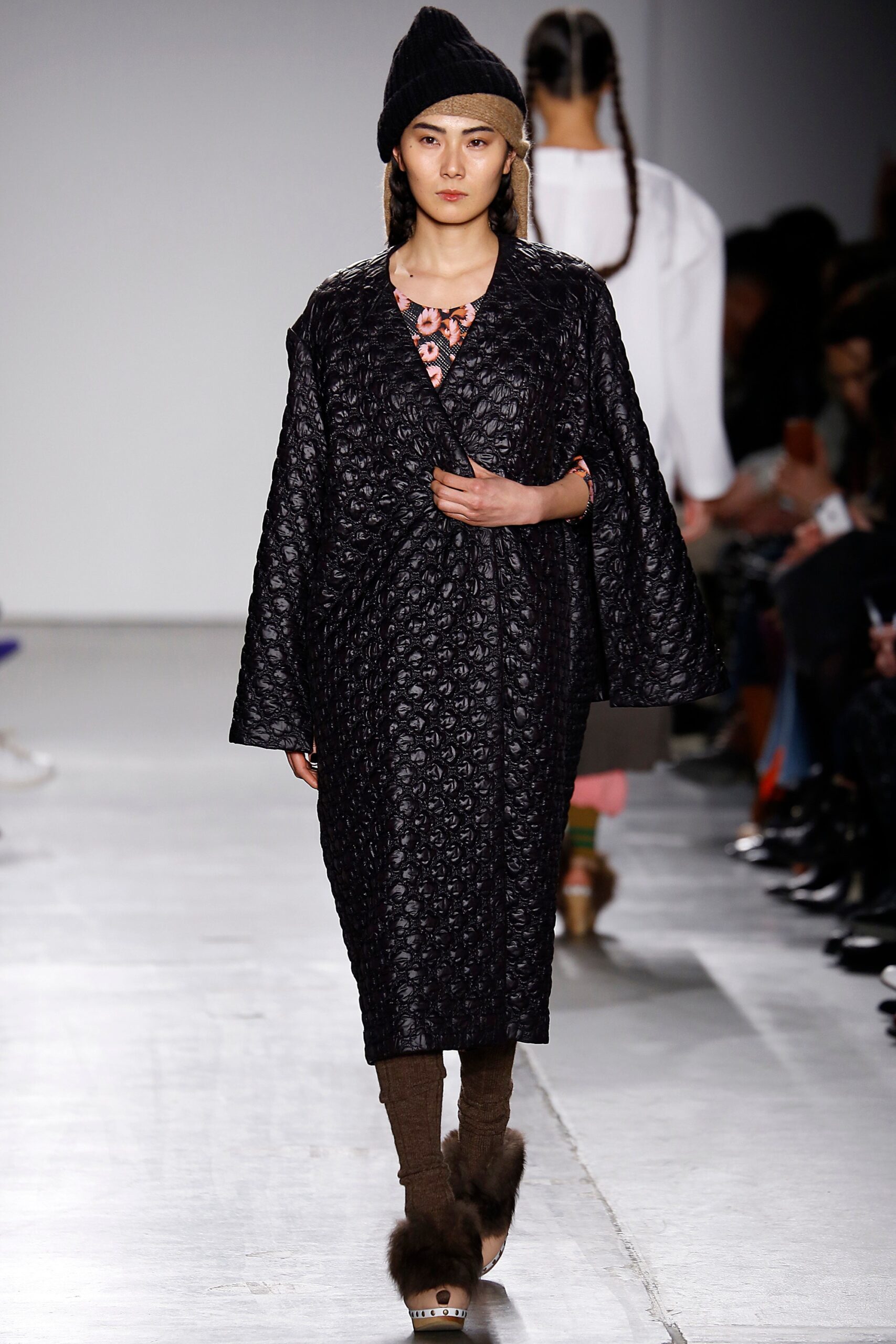 A relaxed black wool coat with long sleeves and a textured finish.
