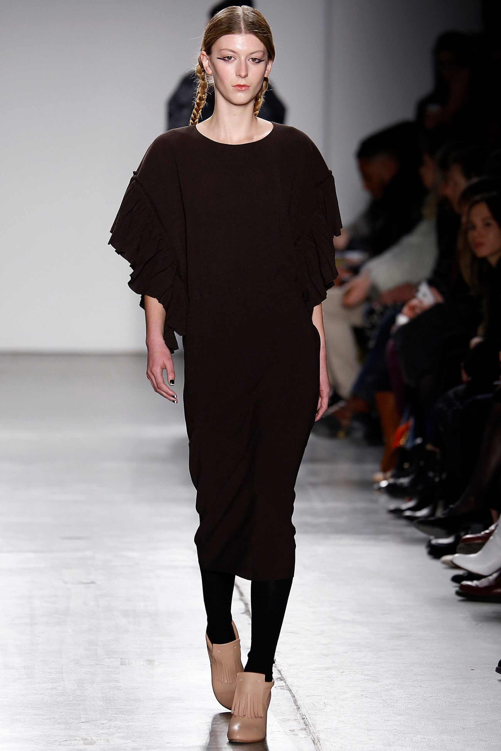 A fitted brown dress with long sleeves and ruffled details.
