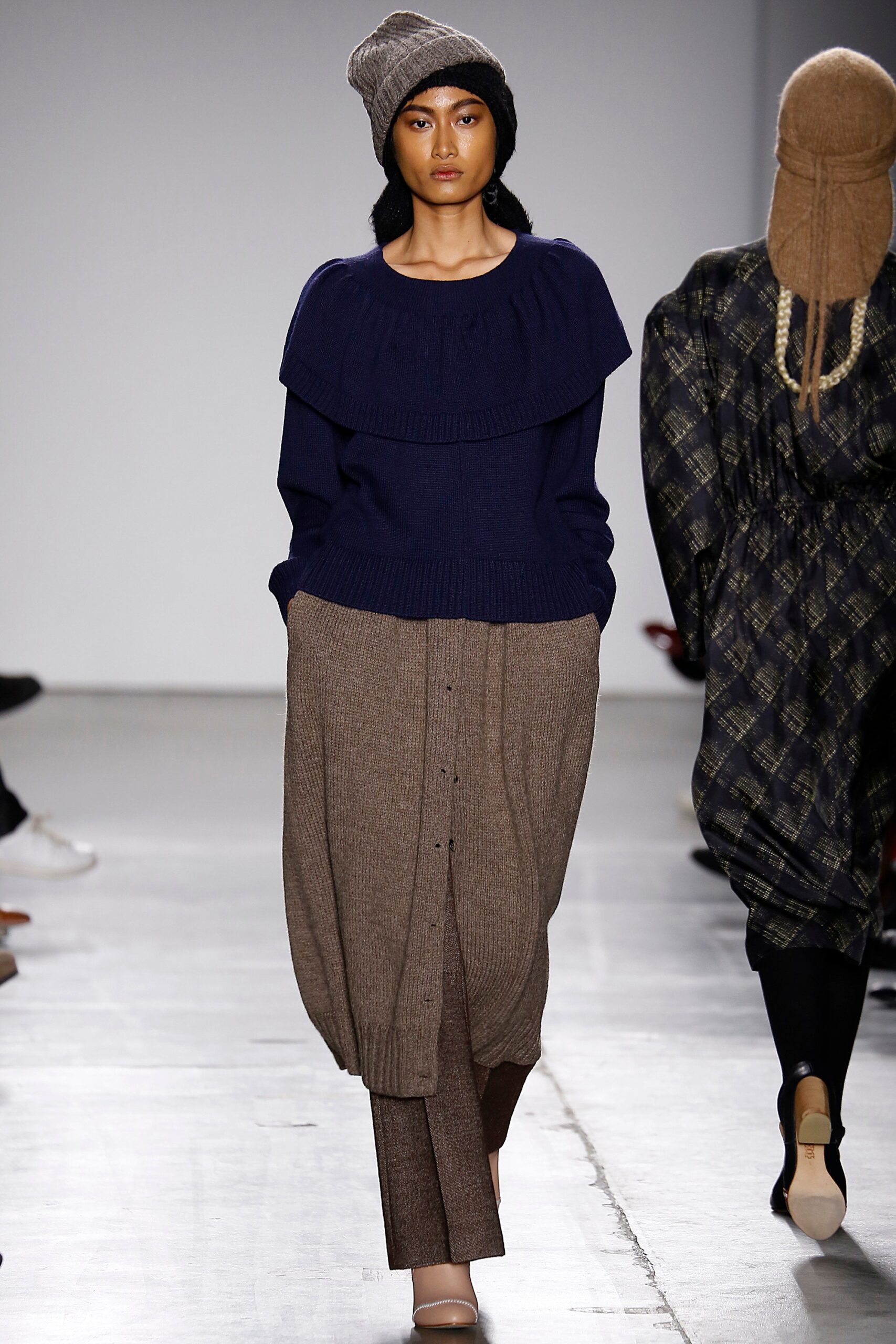 A relaxed navy wool long-sleeve sweater layered over brown cotton pants.