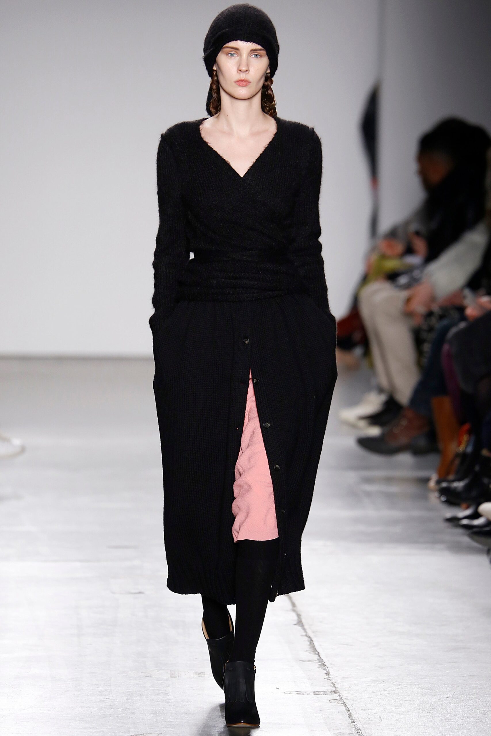 A fitted black knit long-sleeve dress with a V-neckline and buttoned tiered design.