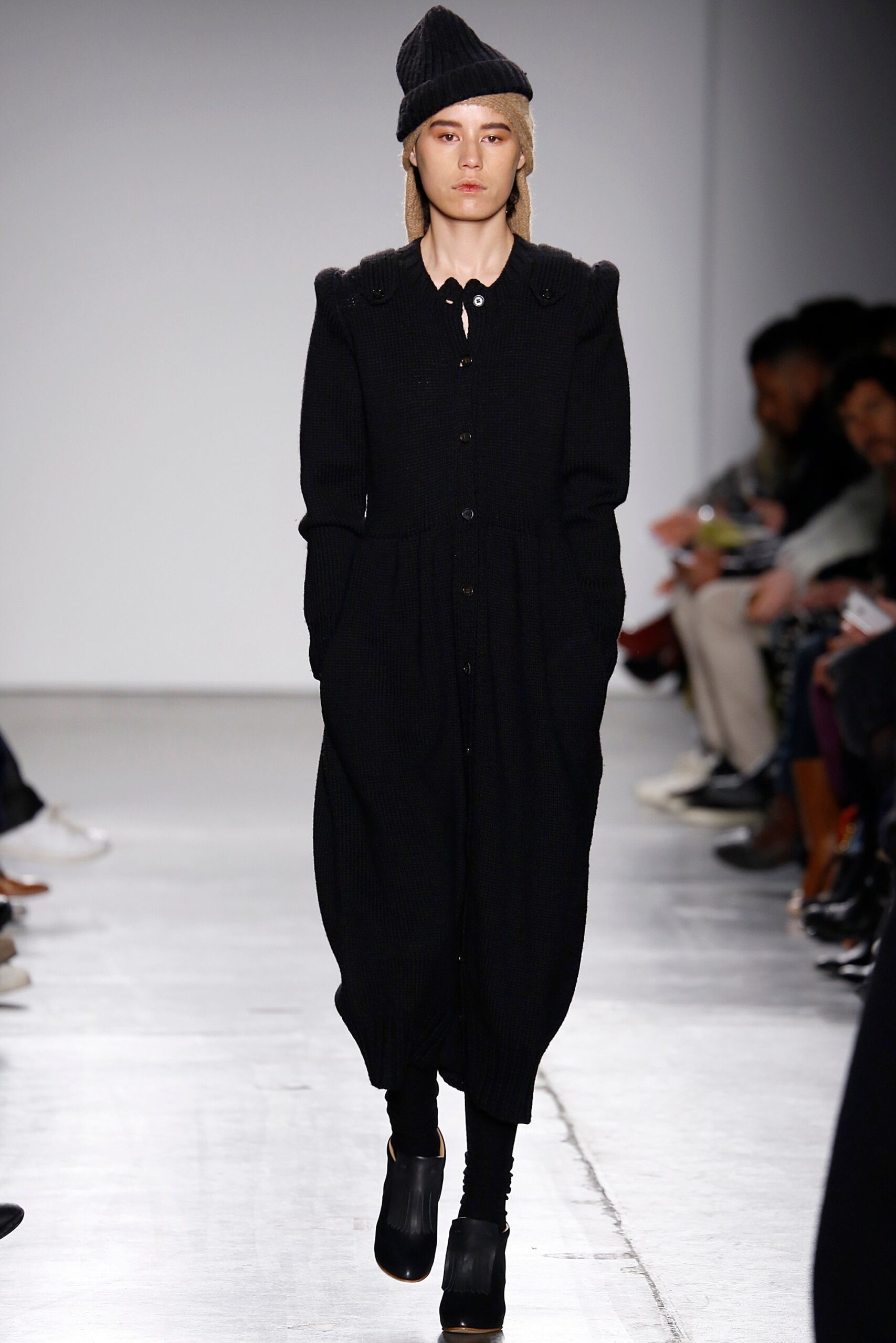 A relaxed black dress with long sleeves and a collared neckline, featuring button details.