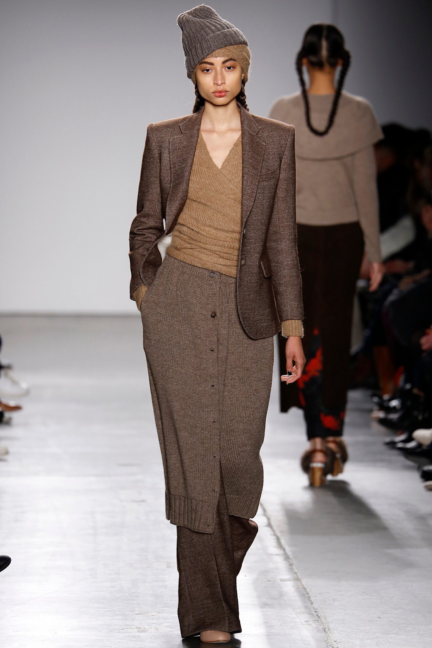A fitted brown wool suit with a long-sleeve top and buttoned design details.