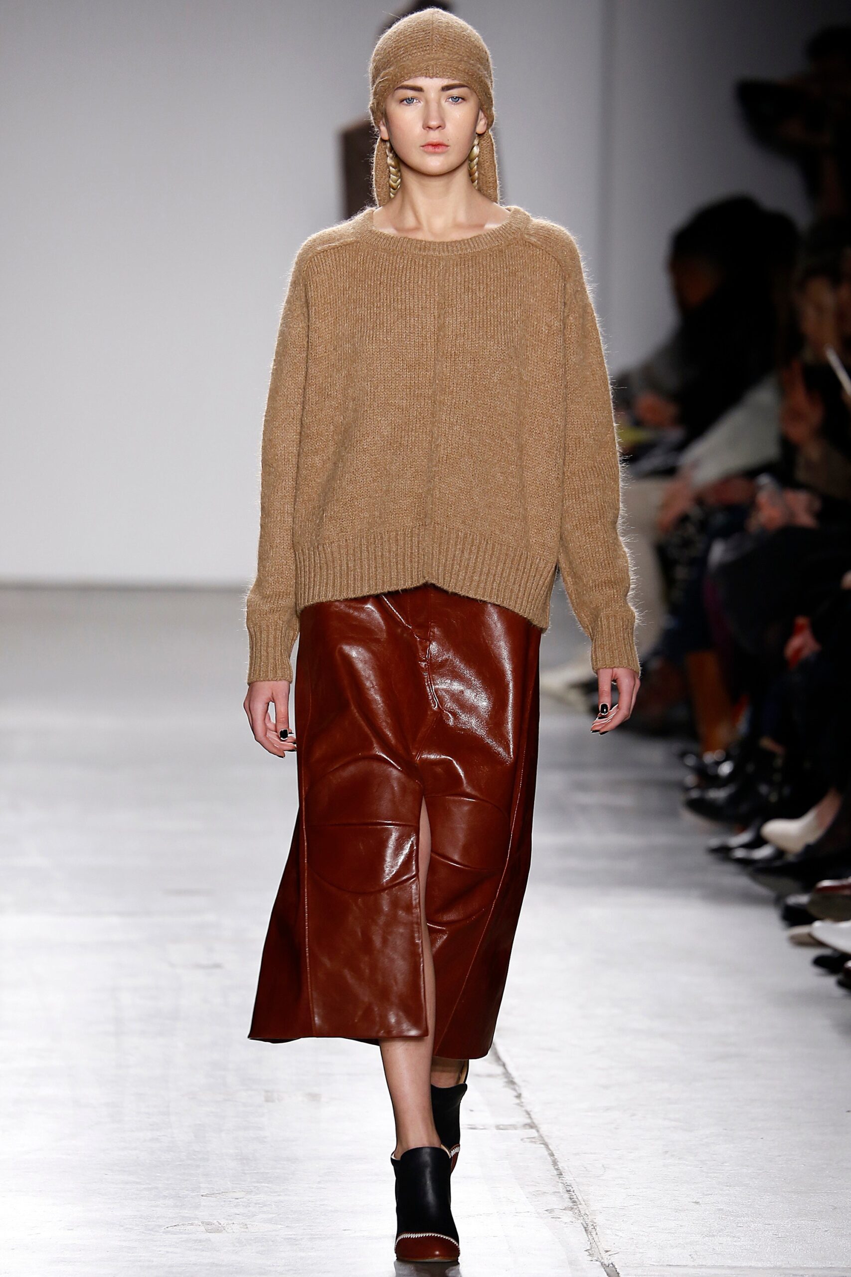 A relaxed brown wool sweater paired with a pleated leather skirt for a chic look.