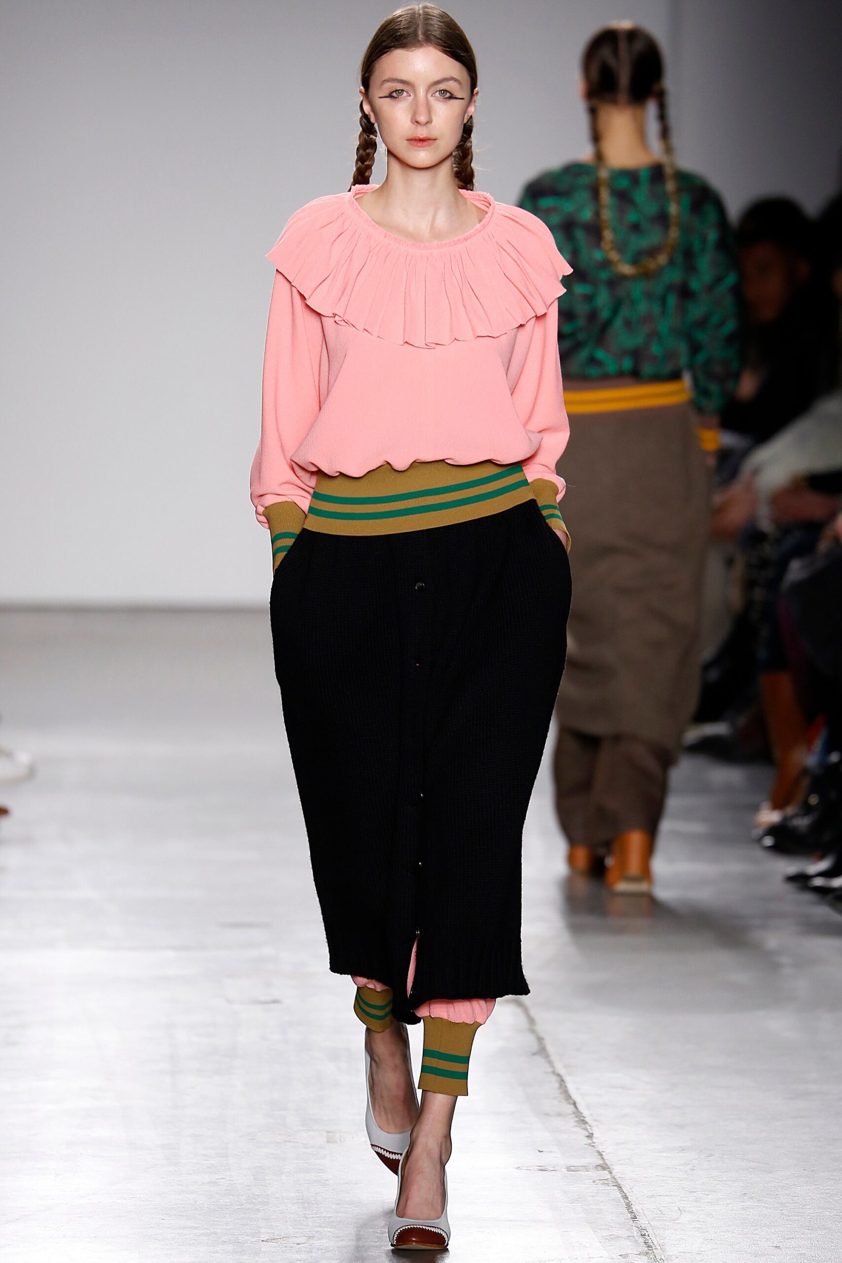 A relaxed pink ruffled long-sleeve top paired with relaxed black pants featuring striped details.