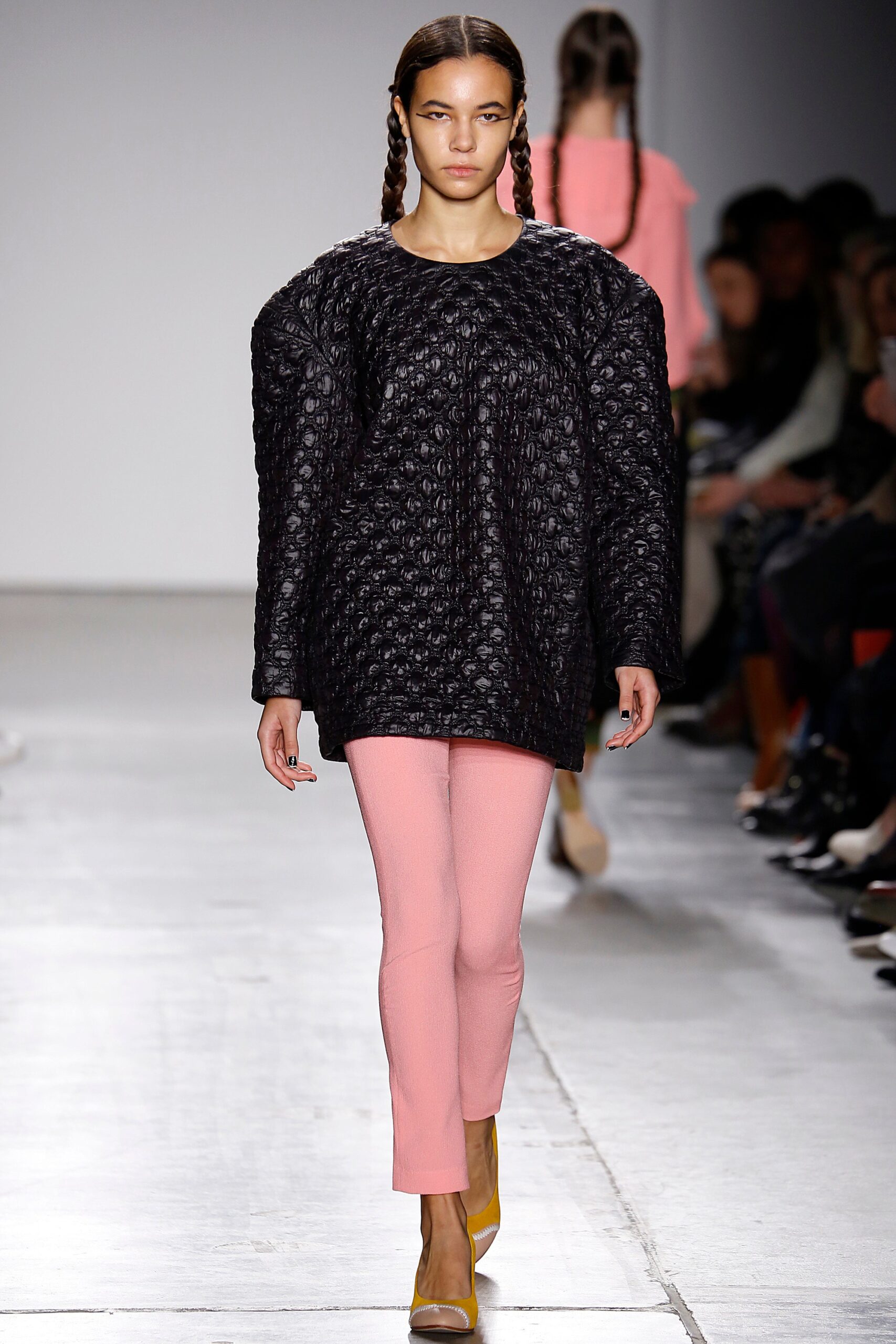 A relaxed black textured sweater paired with fitted pink pants for a stylish look.