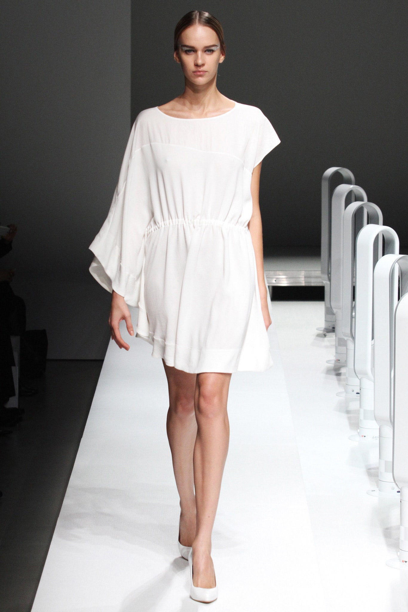 A relaxed white sleeveless dress with a round neckline and asymmetric design.