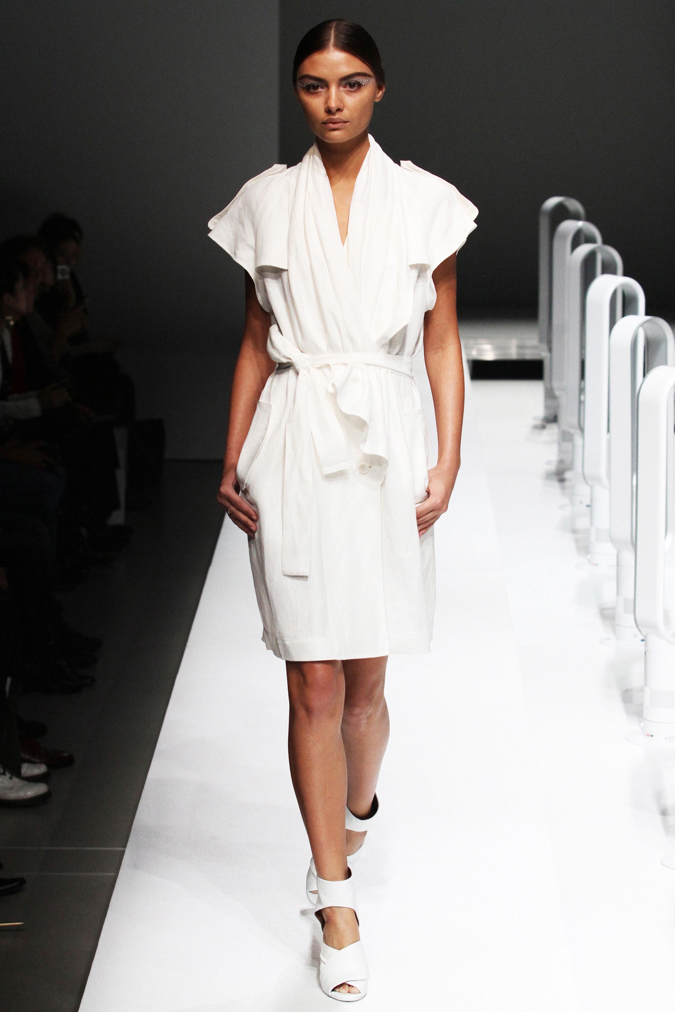 A fitted white sleeveless dress with a collared neckline and belted detail.