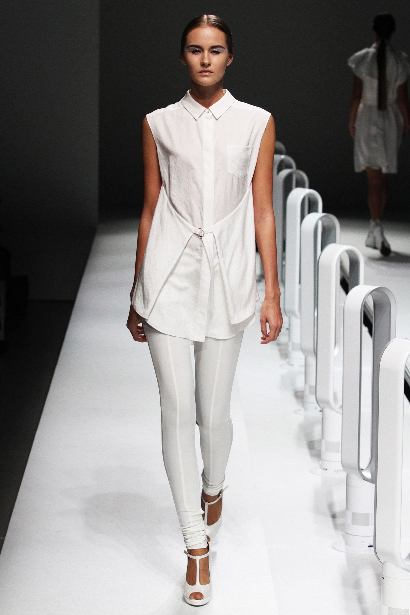 A fitted white collared sleeveless shirt with an asymmetric design paired with white leggings.