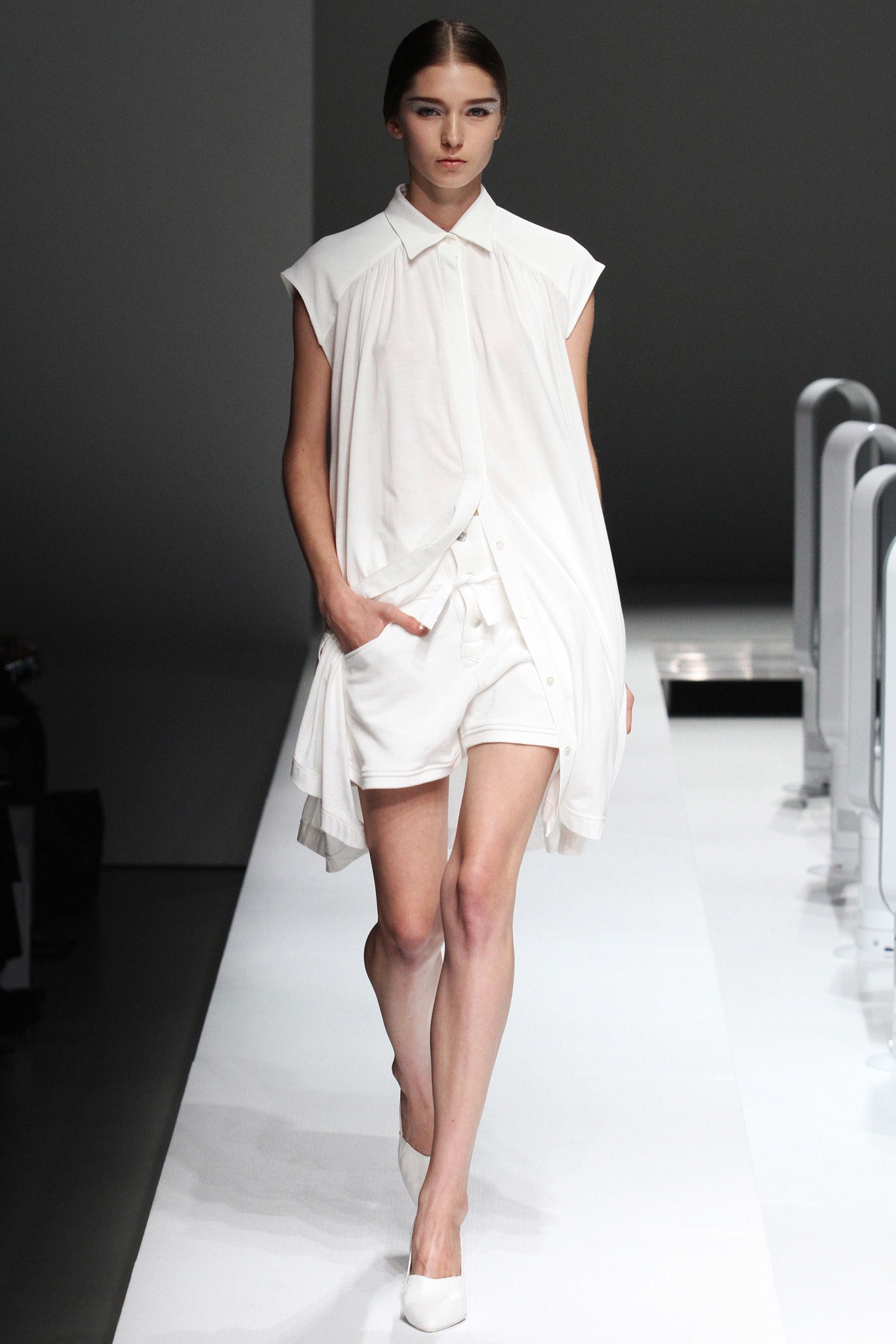 A relaxed white sleeveless dress with a collared neckline and asymmetric design.