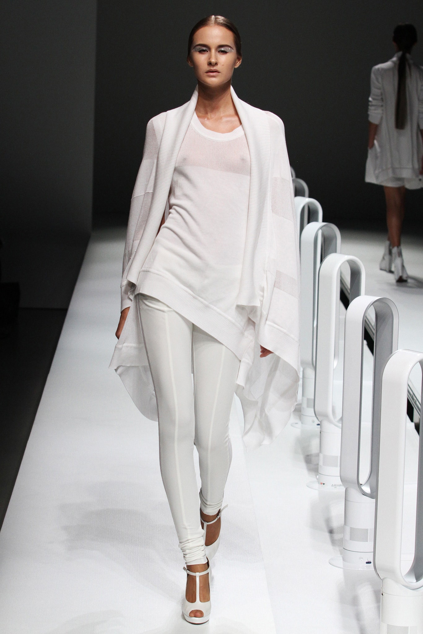A fitted white top with long sleeves and layered design paired with white leggings.