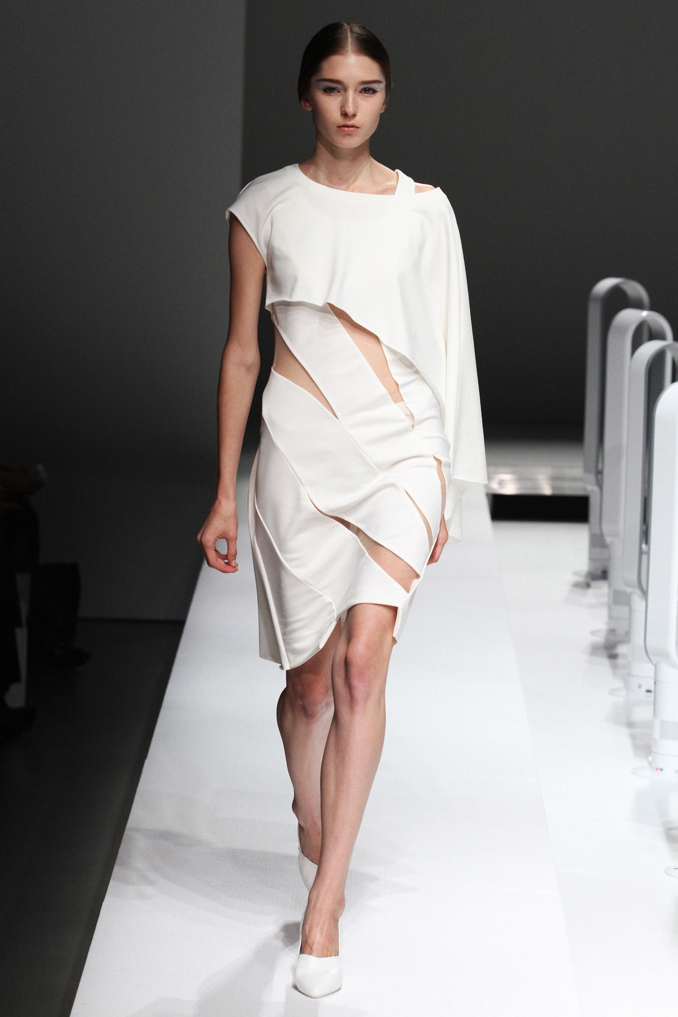 A fitted white dress featuring cutouts and an asymmetric design for a modern look.