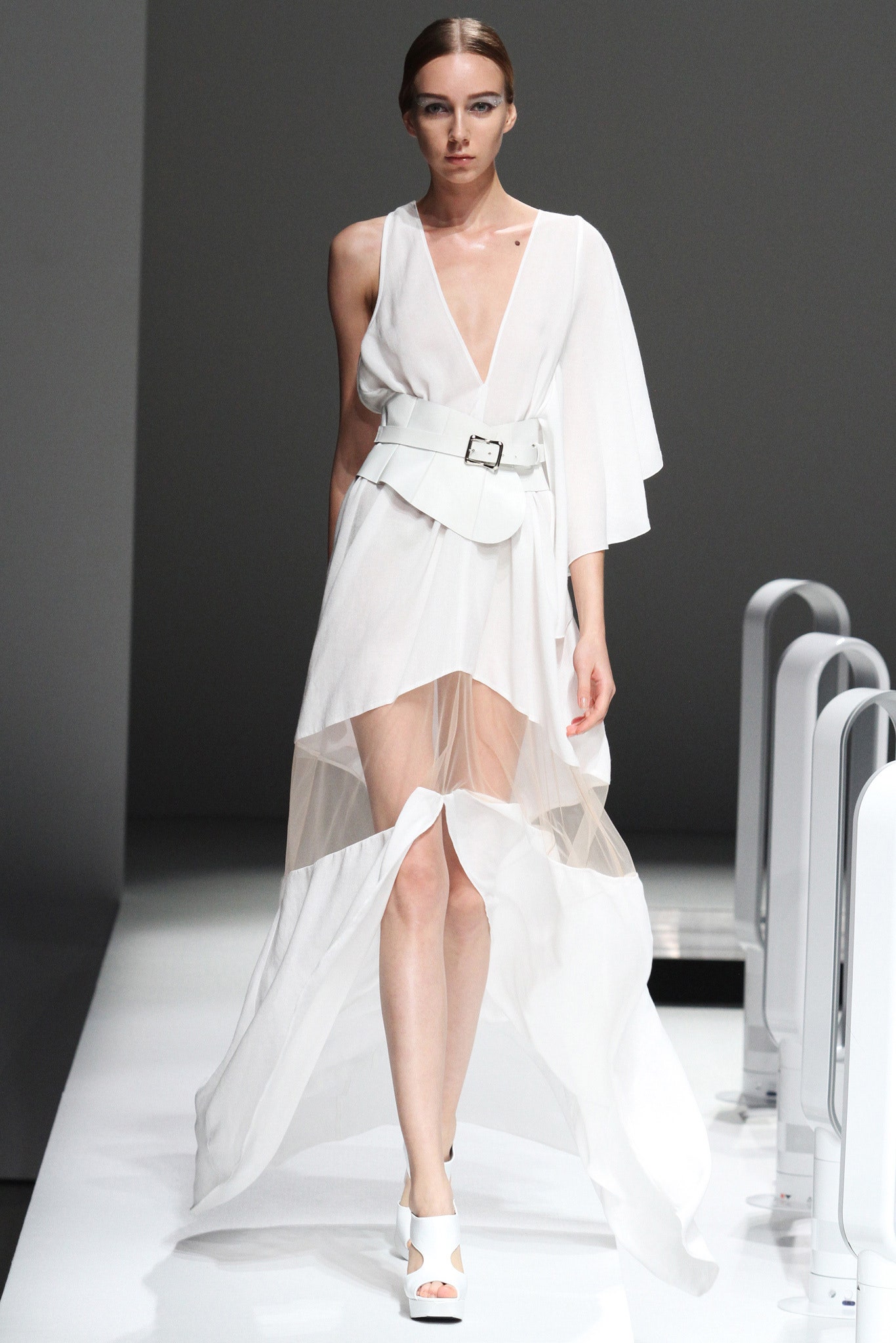 A fitted white silk sleeveless dress with a V-neckline and asymmetric tiered design.