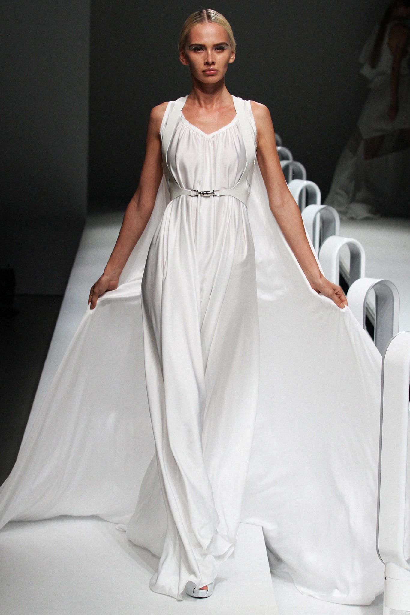 A fitted white silk sleeveless gown with a V-neckline and draped design.
