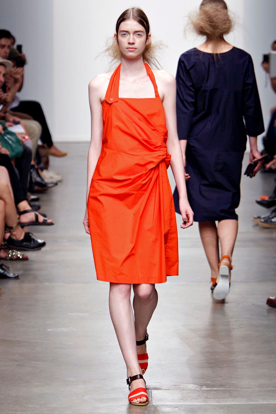 A fitted orange cotton sleeveless dress with a halter neckline and asymmetric design.