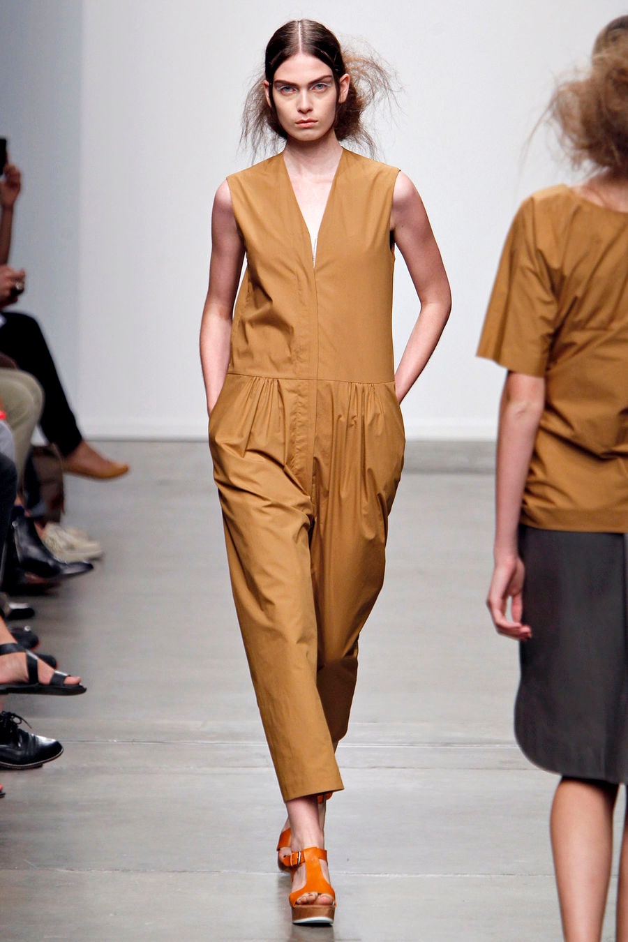 A relaxed brown cotton sleeveless jumpsuit with a V-neckline and pleated details.