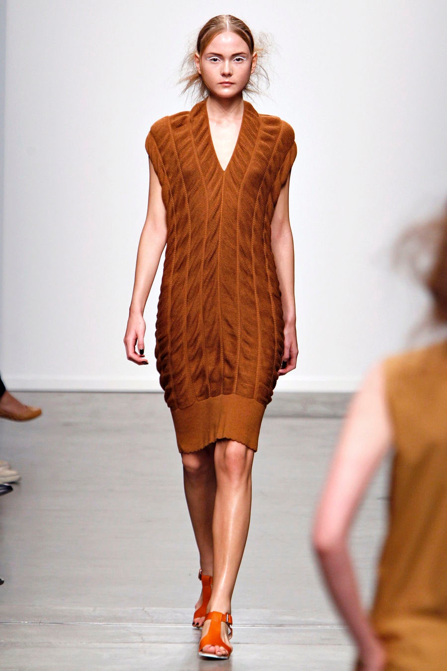 A fitted brown wool dress with a sleeveless design and V-neckline featuring a ribbed texture.