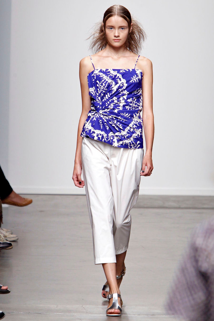 A relaxed blue printed sleeveless top paired with white pants for a chic look.