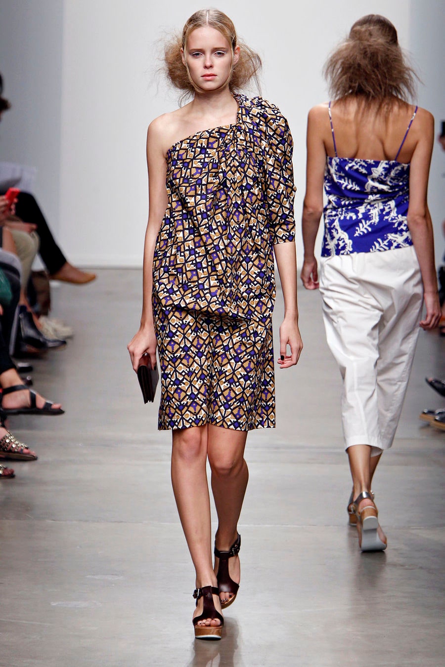 A fitted sleeveless dress with an asymmetric design and vibrant blue and yellow print.