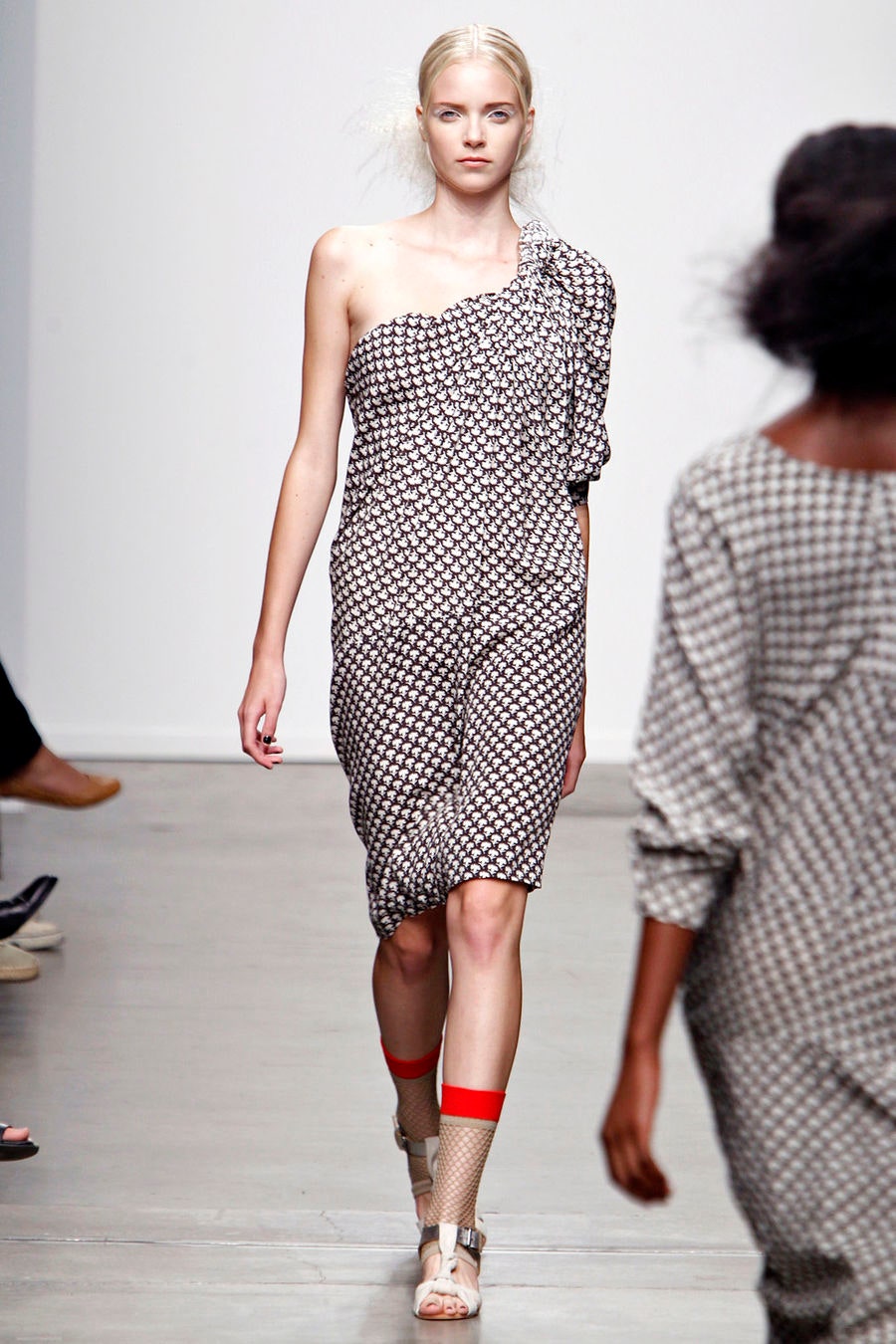 A fitted black and white printed dress with an asymmetric design and sleeveless construction.