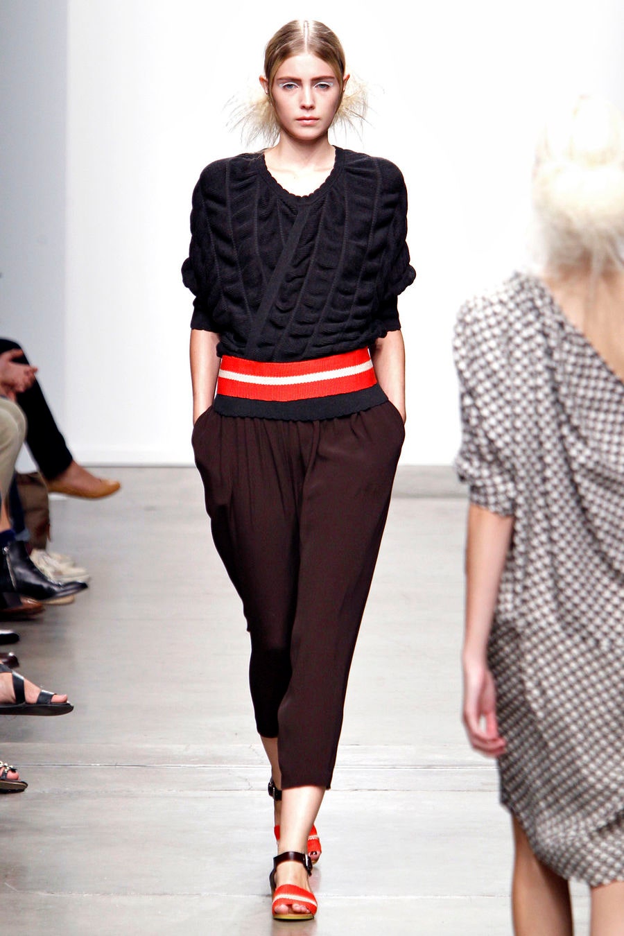 A relaxed black cotton top with short sleeves paired with brown pleated pants.