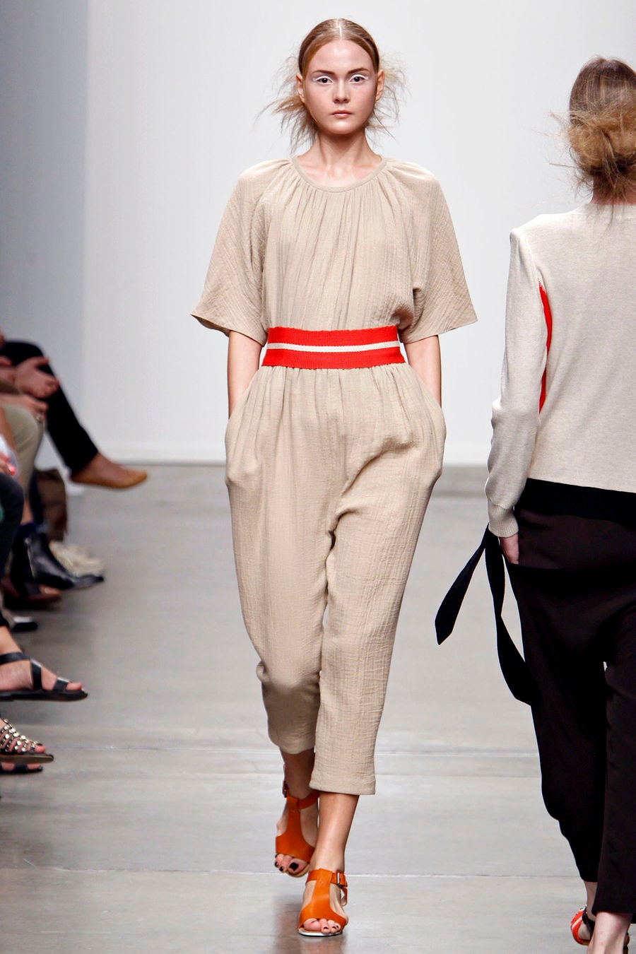 A relaxed beige cotton jumpsuit with short sleeves and pleated detailing.