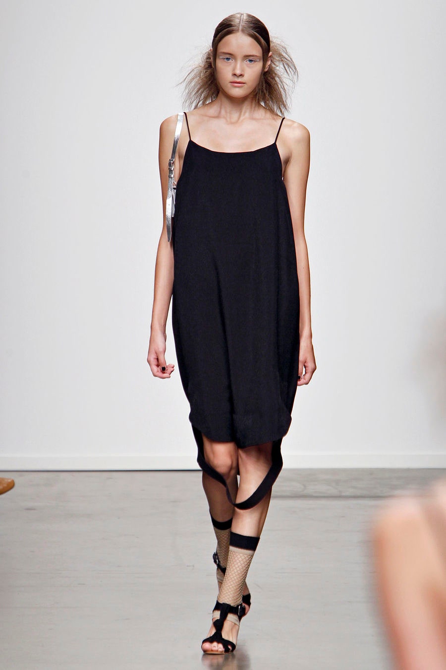 A relaxed black sleeveless dress with a V-neckline and asymmetric design detail.