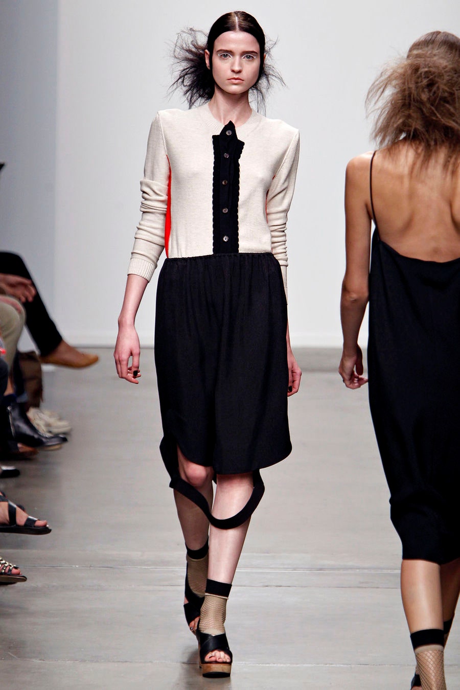 A fitted black and beige dress with long sleeves, a collared neckline, and an asymmetric design.