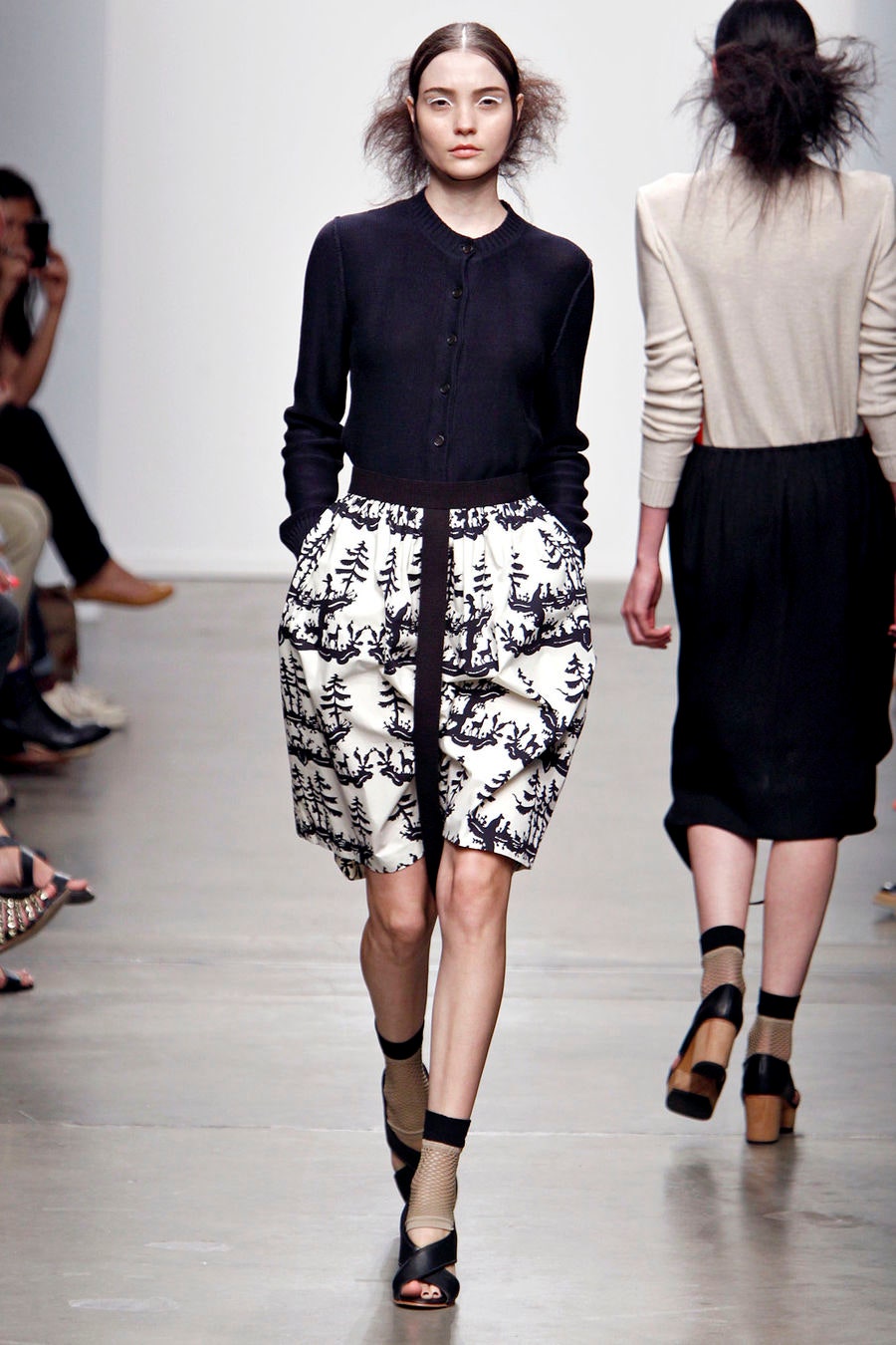 A fitted black blouse paired with a pleated printed skirt, creating a stylish ensemble.