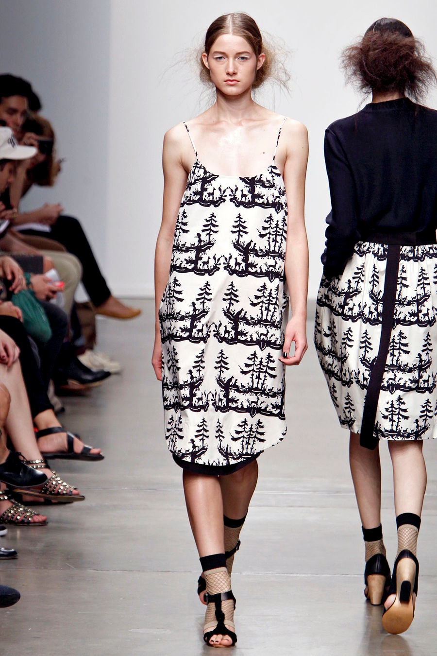 A relaxed white dress with a black tree print, featuring a sleeveless design and V-neckline.