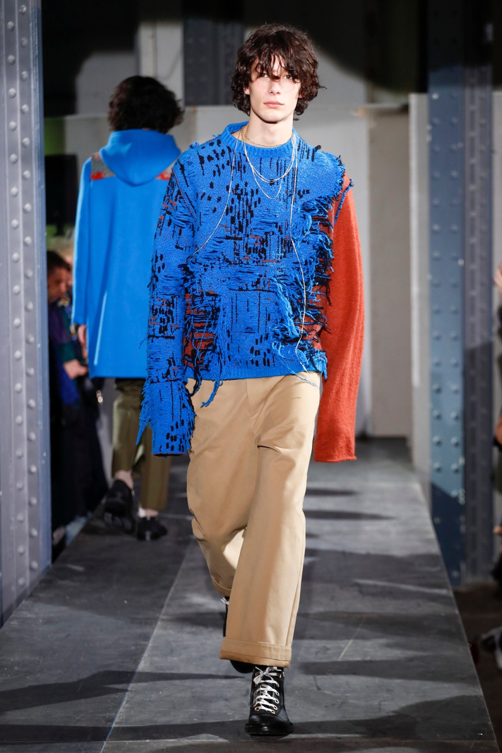 fringed blue and red sweater with beige pants