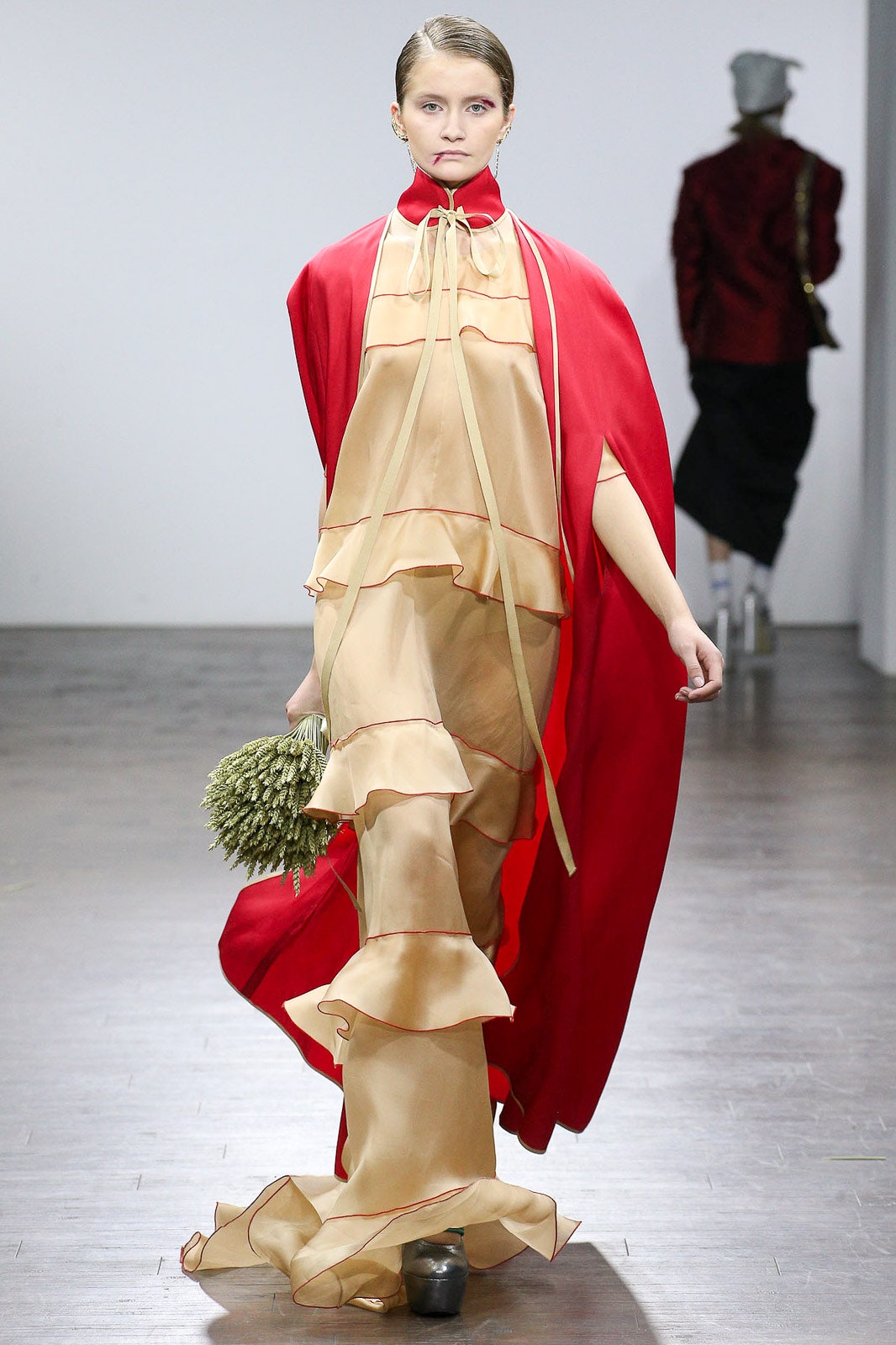 beige silk ruffled gown with red cape