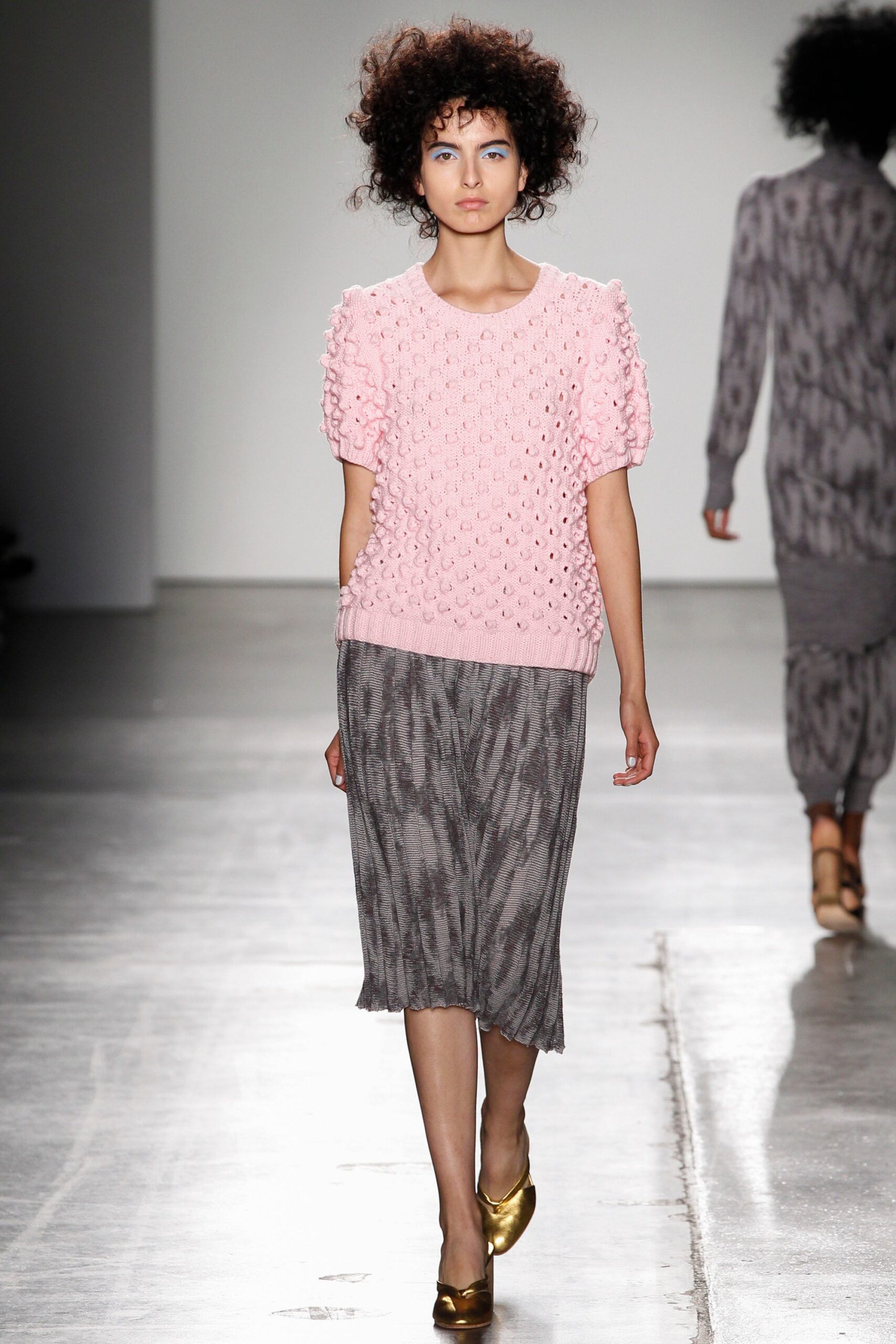 A fitted pink textured top with short sleeves paired with a fitted gray pencil skirt.