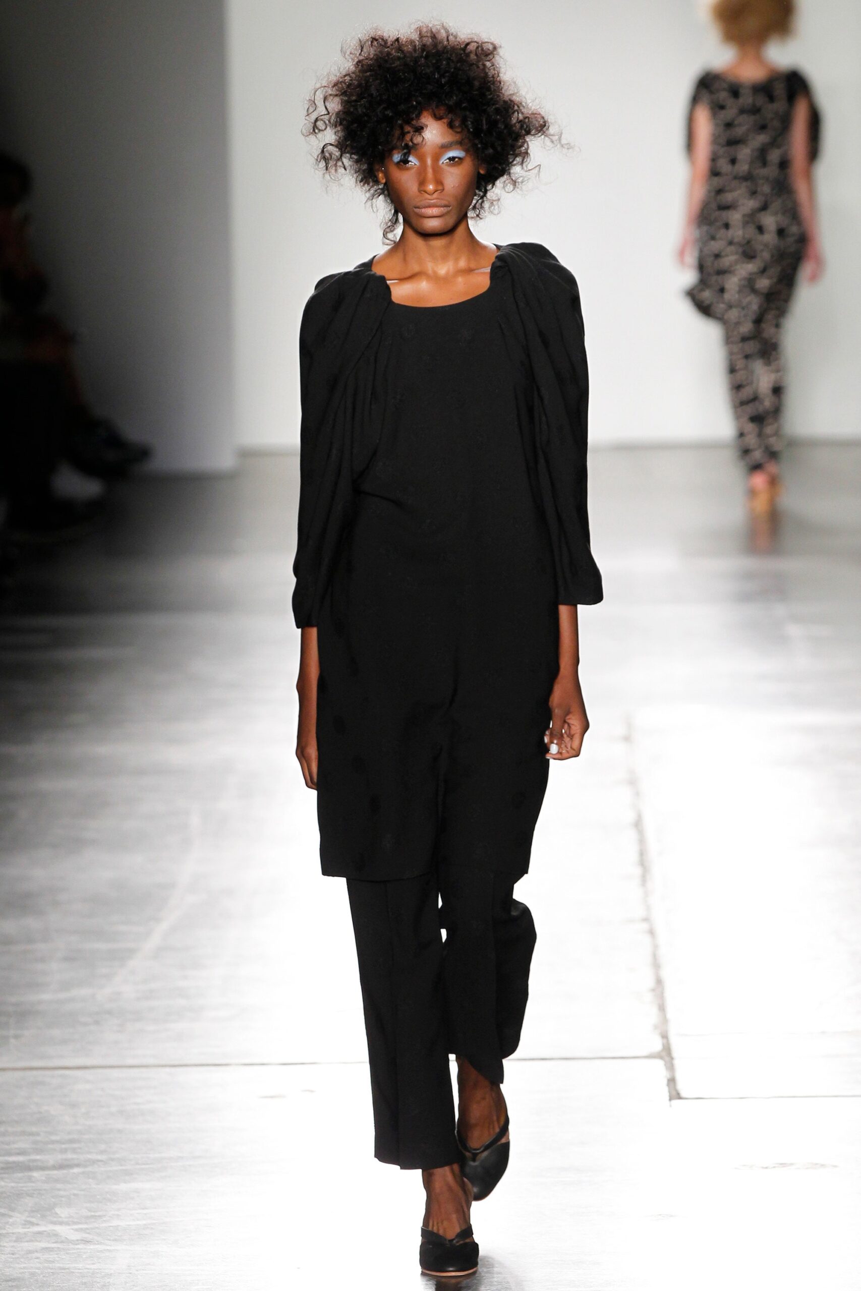A relaxed black jumpsuit with long sleeves and a collared neckline featuring a straight-leg silhouette.