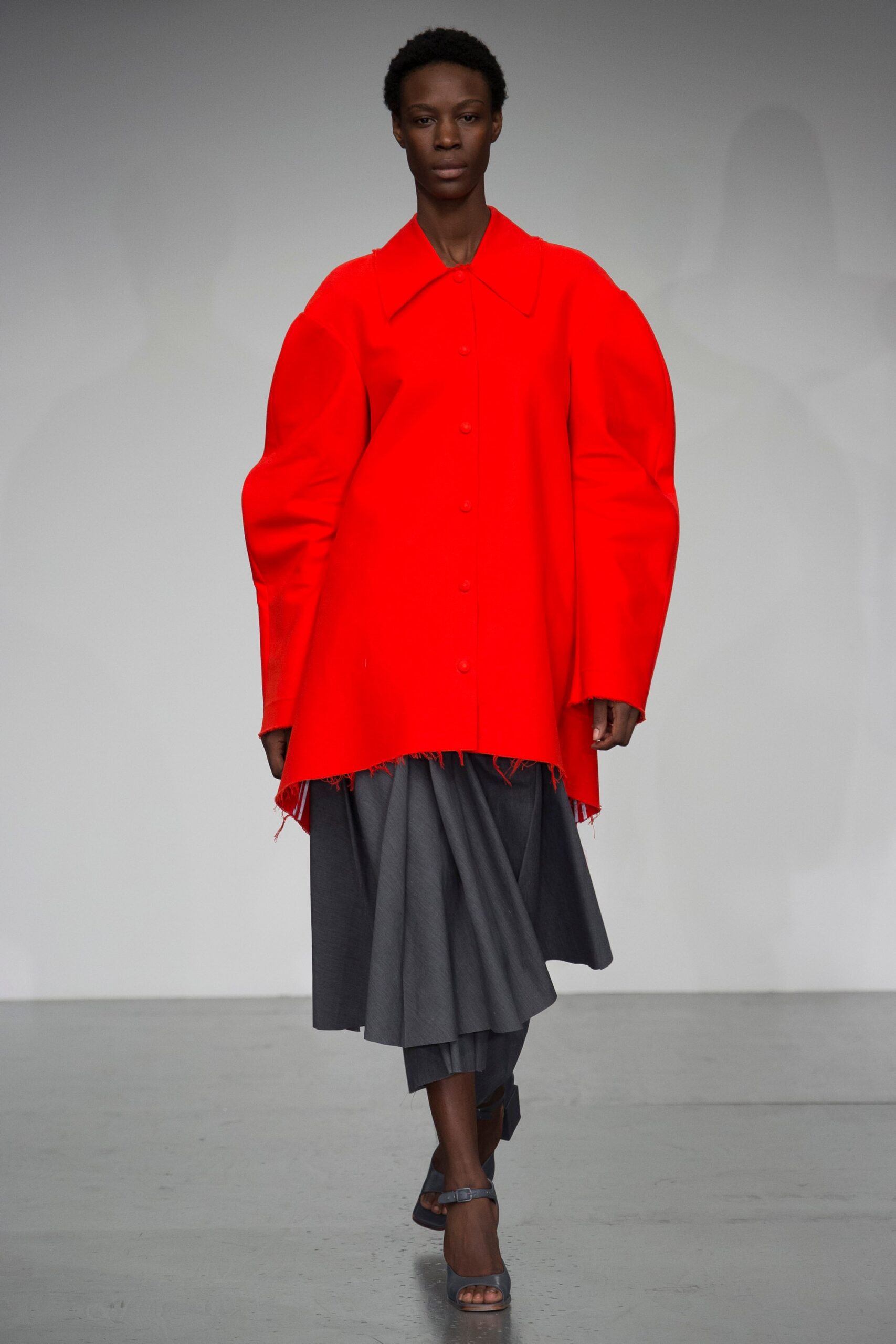 oversized red coat with pleated gray skirt