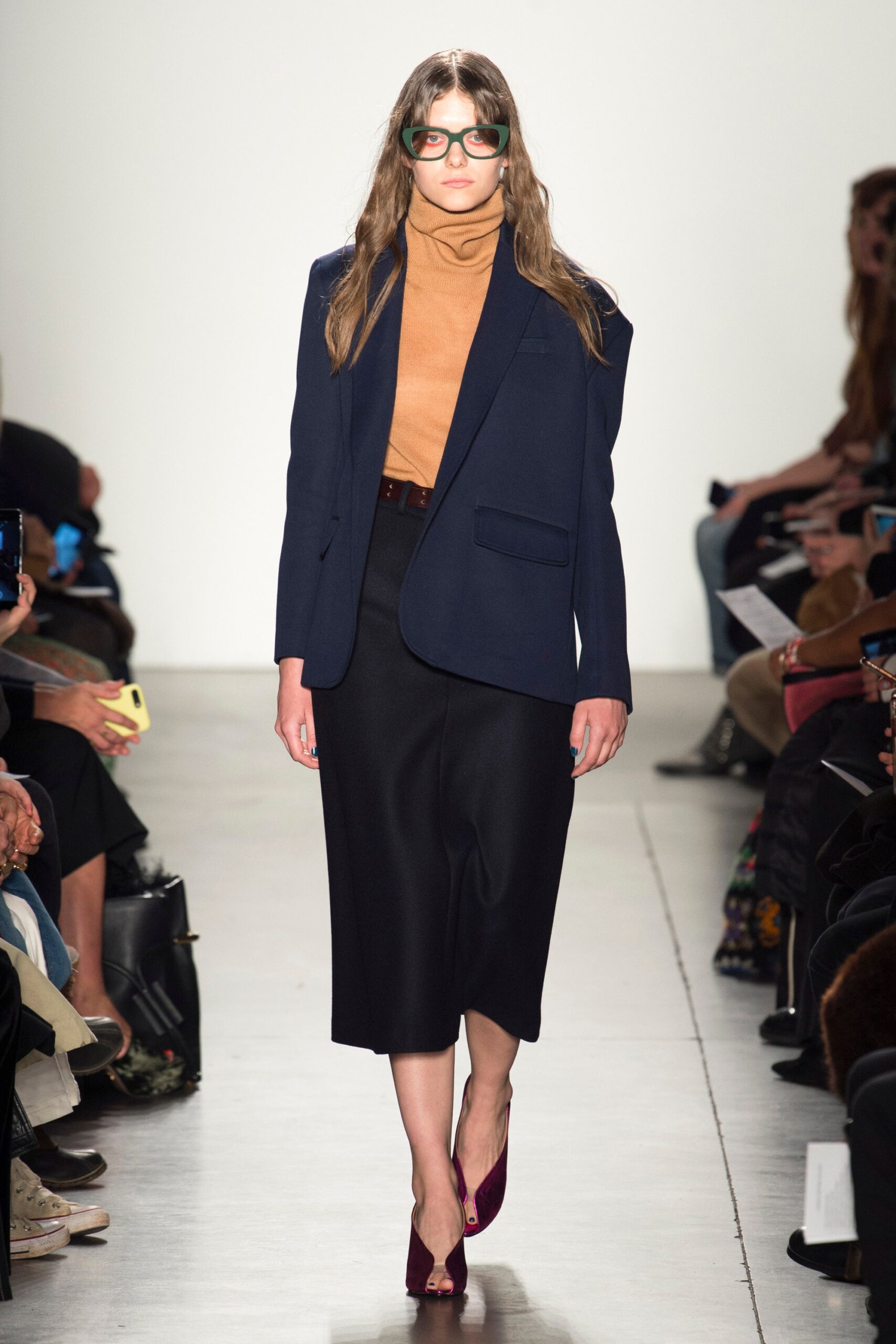 A relaxed navy blazer paired with a pleated black skirt, featuring a collared design.