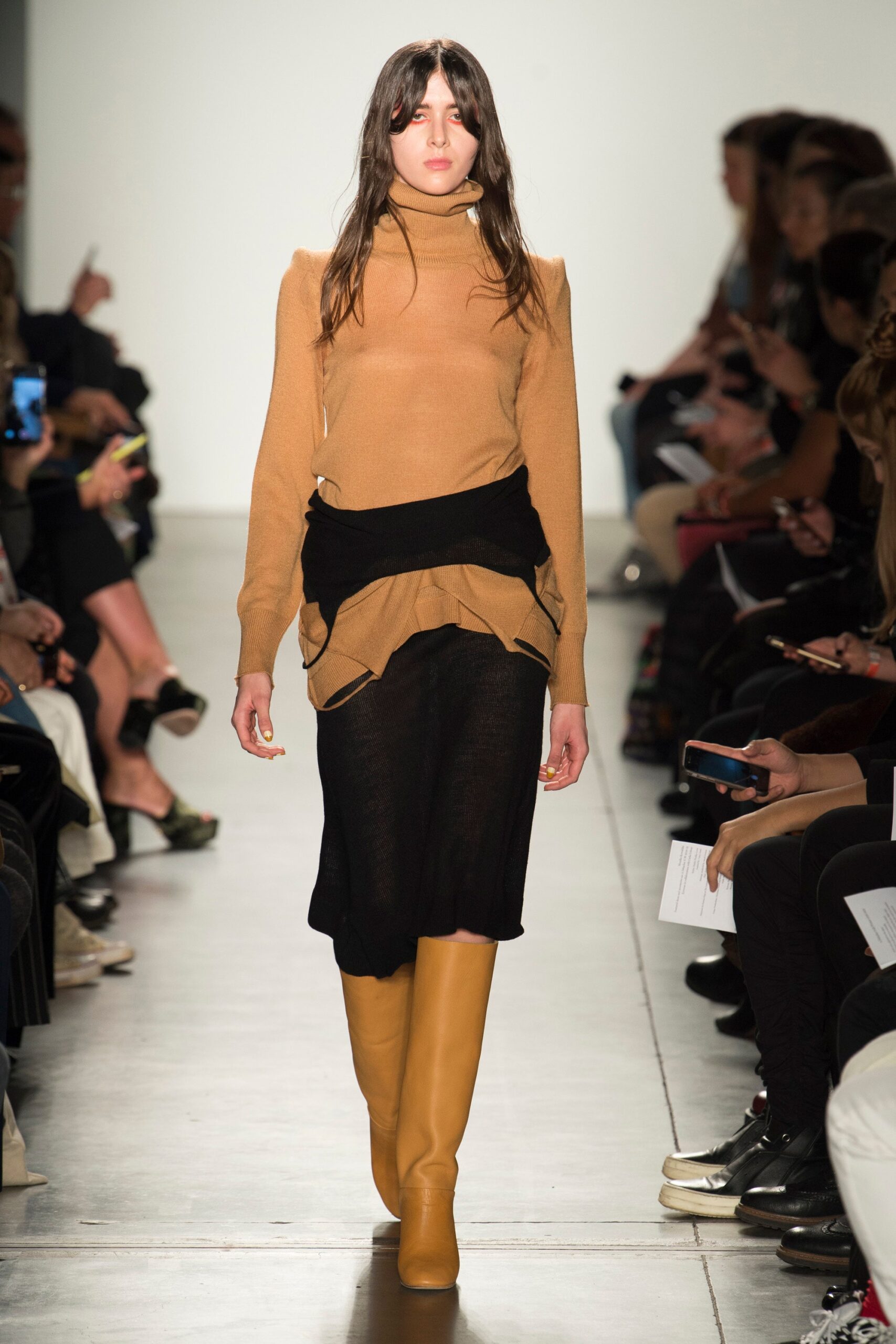 A fitted brown long-sleeve top layered over a black asymmetric dress.